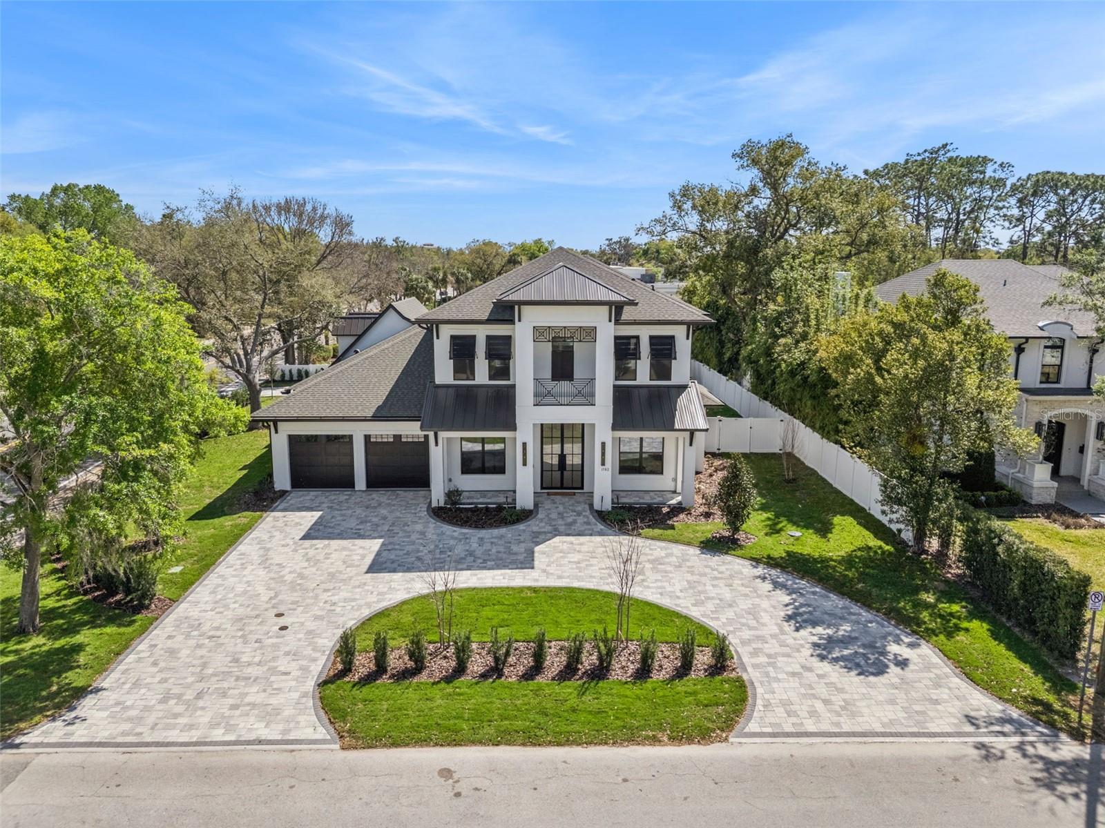 Step into this stunning West-Indies inspired luxury home crafted by Nautilus Homes, where tropical charm meets timeless elegance. An architectural masterpiece in the heart of City of Winter Park. This five-bedroom seven-bath home that includes a private in-law suite offers plenty of exquisite interior features. The home welcomes you with a beautifully designed 16 ft wide circular driveway wrapped in upgraded pavers, offering both elegance and functionality. A very rare 4-car garage in Winter Park with two in the rear and two in the front of the home. Starting with entering through massive 10 ft. double iron doors flowing into the foyer with 11ft high ceiling beginning with the flex/office room and formal dining to your left and right. Followed by entering the gallery that leads to the great room. The Chef’s Kitchen, a culinary dream featuring an oversized center island, quartz countertops throughout, custom 42"+15" wood cabinetry, a custom walk-in pantry, and top-of-the-line Thermador professional series. That Includes a 48' refrigerator, 48" gas cooktop, custom hood, dishwasher, built-in microwave, double convection ovens and built in coffee station. On your way to the formal dining, you pass by the show-stopping, Tempered glass wine room. Its crystal-clear glass enclosure offers a striking view of your curated collection, while the built-in wine chiller ensures each bottle is perfectly preserved. This elegant transition creates a seamless blend of function and sophistication, setting the tone for unforgettable dining experiences just steps away. The primary suite offers tranquility peace of mind, and the primary bath has a spa-like oasis with a spacious shower stand-alone tub. Followed by a custom closet thoughtfully design with plenty of room and storage. The guest retreat area has a huge bedroom, access to a full bath including private access to the Lania and pool. Tucked away with its own private entrance attached to the rear garage, the in-law suite above the garage offers the perfect blend of comfort and independence. This thoughtfully designed space includes a full bath, a cozy living area, and a convenient space with a kitchenette—ideal for extended stays or multi-generational living. Make your way to the second floor that has 11ft ceilings as well. As you reach the top the space opens into a massive game room with a wet bar, perfect for entertainment retreat with a balcony. All second-floor bedrooms have a thoughtfully design with a full bath for privacy. As you make your way back downstairs to outside, step through the oversized sliding glass doors and into your private outdoor oasis. Effortlessly extending your living space into the open air. Just beyond, the sparkling gas heated/saltwater pool and spa framed by lush landscaping and designed for both relaxation and recreation. Also, the fully equipped summer kitchen features gas grille, beverage refrigerator and ample counter space—perfect for alfresco dining and effortless entertaining. This seamless indoor-outdoor flow creates the ultimate setting for enjoying the Florida lifestyle in style and comfort. This masterpiece is equipped with a full irrigation system around the home, exterior lighting, exterior cameras for security. Smart home system ready for lighting, music and security controlled by Control 4 system for your convenience.  Interlachen Golf community less than 5 min, Phelps Park walking distance, Park Ave 10 min and restaurant and retail minutes away.