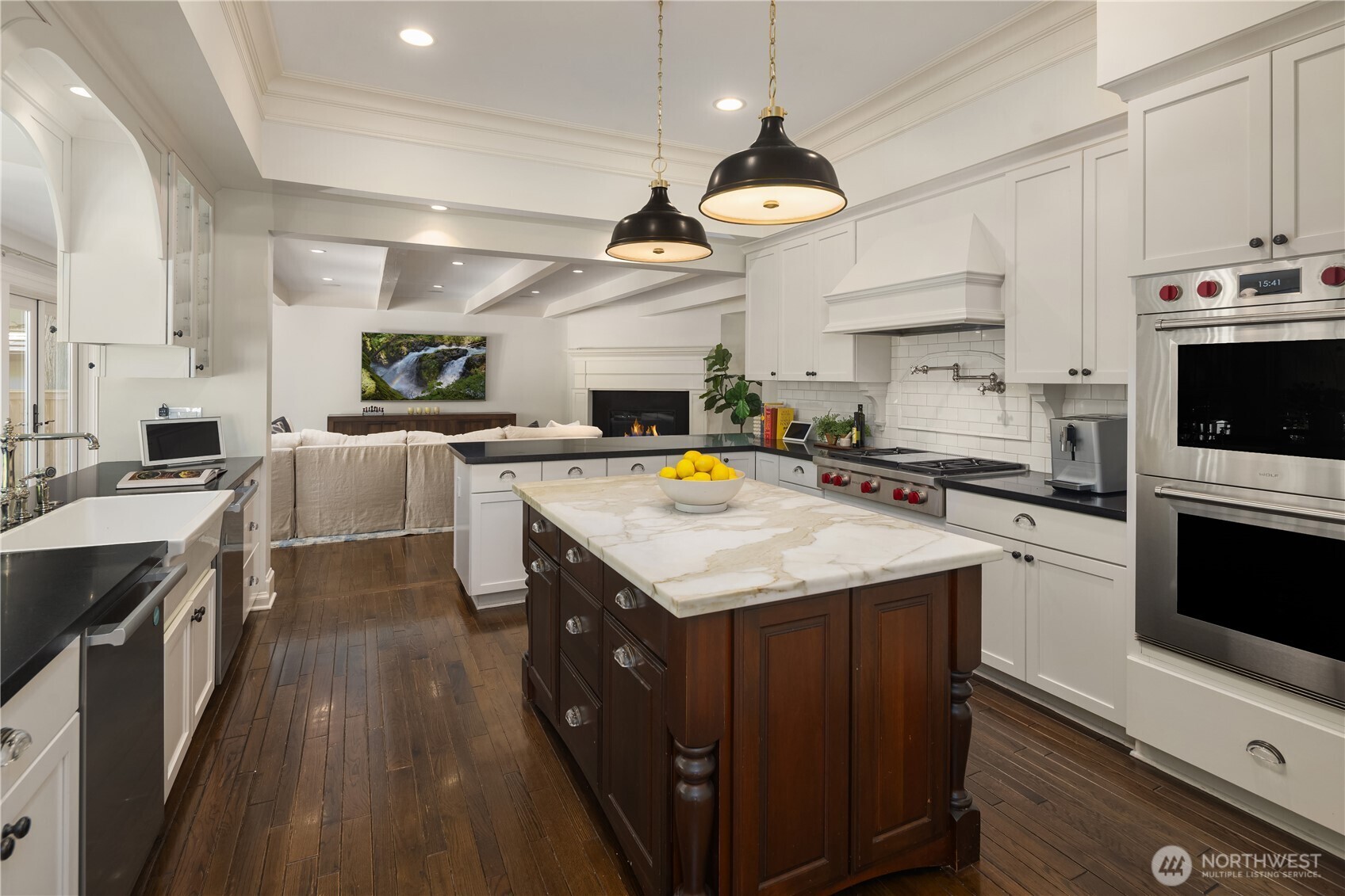 Marble-topped island anchors this kitchen beneath blackened pendant lighting