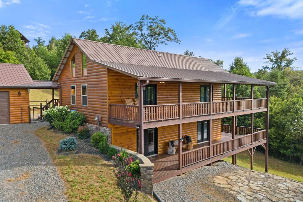 MOUNTAIN CABIN -  Beautiful home offering open concept with soaring tongue & groove ceilings, spacious great room with gas log fireplace and lots of glass to view the beautiful scenery just out your doors. Primary suite on main level with walk out doors to sweeping covered deck.  Second bedroom on main level also with private entry to amazing covered deck. Terrace level features two additional bedrooms, full bathroom and large family room with Green Mountain wood burning stove.   Entire terrace level also has extra large covered deck with access from bedrooms and family room.  Detached two car garage finished and insulated with attached carport including a 2nd roll up door and breezeway just steps to front door.  Home is partially furnished with furniture in all bedrooms and family room. Large front load washer and dryer also included.   And for your Fur Baby, fenced in area off porch with ramp for easy entry.   Brownings Safe installed on terrace level for all your special items.  Western North Carolina living at its best with tubing, hiking, fishing, bird watching, kayaking, horseback riding, boating and so much more only minutes away from your luxury home. Visit North Georgia Fairgrounds in nearby Hiawassee, Ga offering concerts with many famous musicians and arts & crafts festivals.  If you like games stop by Harrah's Casino in your home town.  Cities like Asheville, Atlanta, Waynesville, Cherokee, Chattanooga  and many more only a few hours away. Schedule your appointment today.