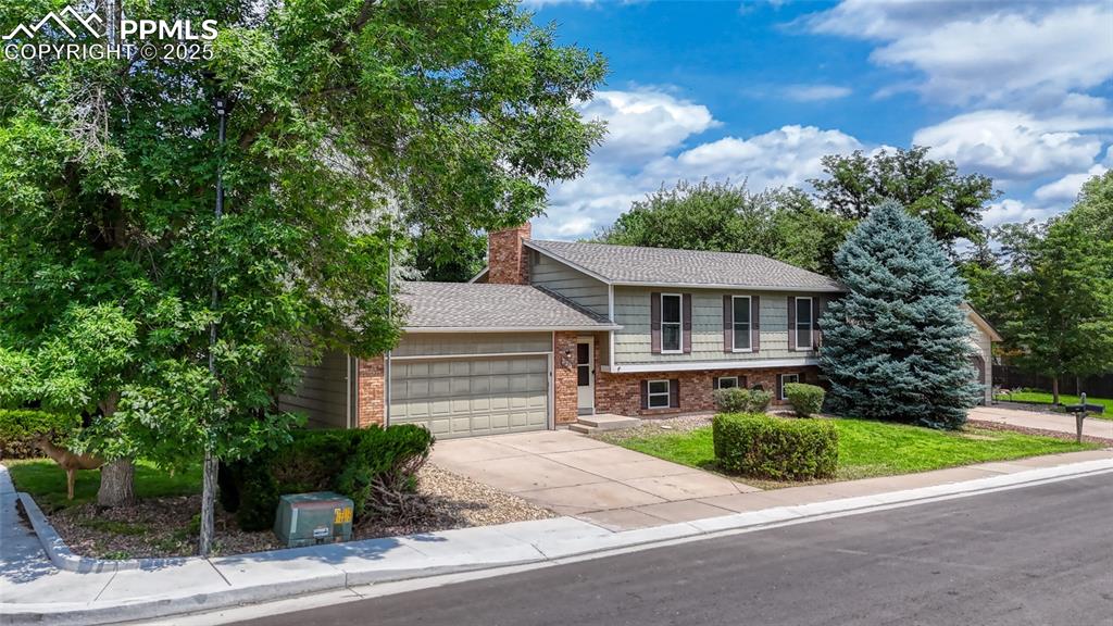 Fantastic Rockrimmon home on a large corner lot with mature trees for perfect privacy.  Great curb appeal w/ professional landscaping & craftsman style siding.  Open floor plan w/ wood laminate flooring and loads of natural light.  Entire interior has new paint.  Beautiful kitchen features white cabinets w/ hardware, slab granite countertops, stainless steel appliances, designer tile backsplash, and walk out slider to wood deck.  Master suite features wood shiplap wall & attached remodeled bathroom w/ slab granite counters, tile shower, updated lighting, and wood laminate flooring.  Lower level features brick fireplace w/ wood stove insert, two additional bedrooms, and another full bathroom.  Oversized garage w/ utility door to the backyard.  Fully fenced backyard.  District 20 schools.  Enjoy.