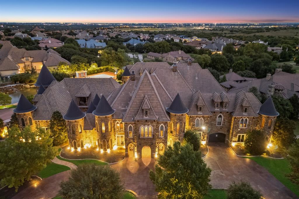 AUCTION: Bidder registration deadline: 3 November. Starting bids expected between $2M–$4M. A commanding architectural masterpiece crowns an exclusive hilltop position within Montserrat, one of West Fort Worth's most prestigious enclaves. This remarkable castle estate spans over two acres of meticulously landscaped grounds, offering an unparalleled lifestyle of grandeur and resort-caliber amenities. Indoor and outdoor pools, private pond, professional sports court, and dedicated guest quarters with a studio to create endless entertainment possibilities. Multiple living spaces flow throughout seven thoughtfully designed bedroom suites, each complemented by spa-inspired baths and custom finishes. The wine room, private theater, custom-designed gymnasium, and owner's suite with a private office above with your own elevator from the primary suite demonstrate extraordinary attention to sophisticated living. This is more than a residence—It’s a J. Lambert Custom Home previously owned and built by the owner of the Texas Rangers!