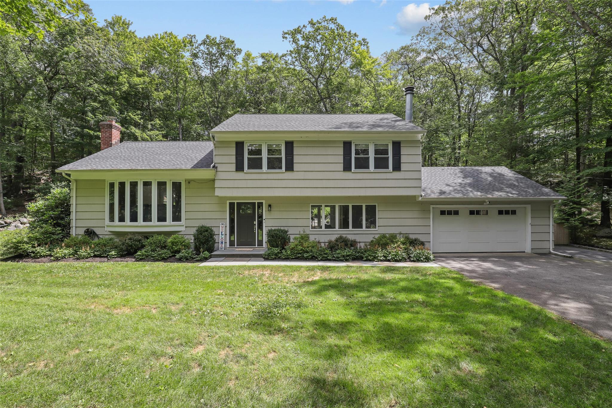 Wonderful Windmill Farms 3 Bedroom plus office split level home privately set on back of cul de sac. This updated and well-maintained bright and modern home features recently refinished hardwood floors, large windows, and beautiful property. The main level includes an inviting family room with built-ins and a lovely fireplace with stone surround, a private office, a mud room, laundry room and full bathroom. Up a small flight of stairs to the kitchen with stainless appliances, granite countertops and a door to the deck, a large living room with built ins, and a dining room with a wall of windows. The upper level has the primary suite with walk in closet, ensuite bathroom and wall of California closet built ins, two additional bedrooms and a hall bathroom. The outdoor spaces include a private deck, a bluestone patio and a level yard with an attractive stone wall. Recent improvements include refinished wood floors, new carpet runners on stairs, new front door, tesla charger, blown in attic insulation, interior painting.  Windmill Farms is a highly desirable community that offers the owners the exclusive opportunity to join the beloved private lake club where they can enjoy the beach, tennis, pickleball, boating, swimming, dining and so much more. Full house generator. House has MEC. Byram Hills Schools