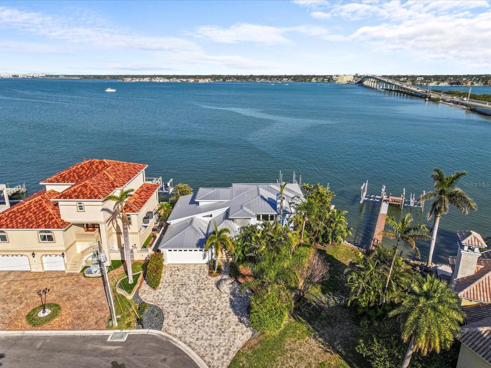 JUST REDUCED 200K! High and dry. This elevated home never flooded during storm and was built to withstand the test of time. This stunning waterfront oasis in highly sought-after Belleair Beach, FL is a one-of-a-kind, coastal contemporary home with water views from every room. That has been exquisitely updated to offer the perfect combination of luxury, comfort, and style. Upon entering this expansive 4-bedroom, 4-bathroom home, you'll be greeted by an abundance of natural light and breathtaking views of the sweeping waterfront vistas of the Intracoastal waterways that stretch as far as the eye can see through the floor to ceiling windows. With 3,335 sq ft of open concept living with 20 foot ceilings and gas fireplace that is designed for both entertaining and relaxation. The living, dining, and entertaining spaces are enhanced by exquisite custom finishes, including new soft close kitchen cabinetry, quartz countertops, and marble tile. The new gourmet kitchen is outfitted with premium appliances complete with a Dacor gas stove, double electric oven and downdraft range hood in the oversized island and Sub Zero refrigerator leaving ample space for both intimate meals and grand entertaining. The seamless transition from the interior to the expansive outdoor living area creates a true indoor-outdoor experience. The first floor primary bedroom, offers panoramic water views through your sliding doors to expansive balcony, a spacious walk-in closet, and a spa-like ensuite bathroom. Upstairs you’ll find beautiful hand scraped wood floors throughout the 3 additional bedrooms and 2 bathrooms, one of which could be the 2nd primary en suite bedroom with its own private balcony. Step outside to enjoy 140 feet of waterfront with the lush landscaping around your beach-entry pool with two waterfalls, a custom outdoor kitchen, new tiki gaslit lamps, new pool pump with gas heater for your spa and a dock with a 16,000 lb boat lift and direct access to the deepwater Intracoastal Waterway. More upgrades include double thermal impact windows and doors, a heavy-gauge metal roof, Air Conditioner, new electrical panels, high volume tankless hot water heater, and a full outdoor renovation with new balconies, driveway, pavers, deck, painting inside and out, and new gas supply to the home. This home is ready for its new owners to sit back and relax. This street recently placed all of the overhead utilities underground. This is more than just a home—it's an entertainer's paradise and boater’s dream. With easy access to pristine Belleair Beach, world class shopping, dining and recreational opportunities, as well as proximity todowntown Clearwater and major airports, this property offers the best of coastal living in one of the most coveted locations in the Tampa Bay area. See video tour below.