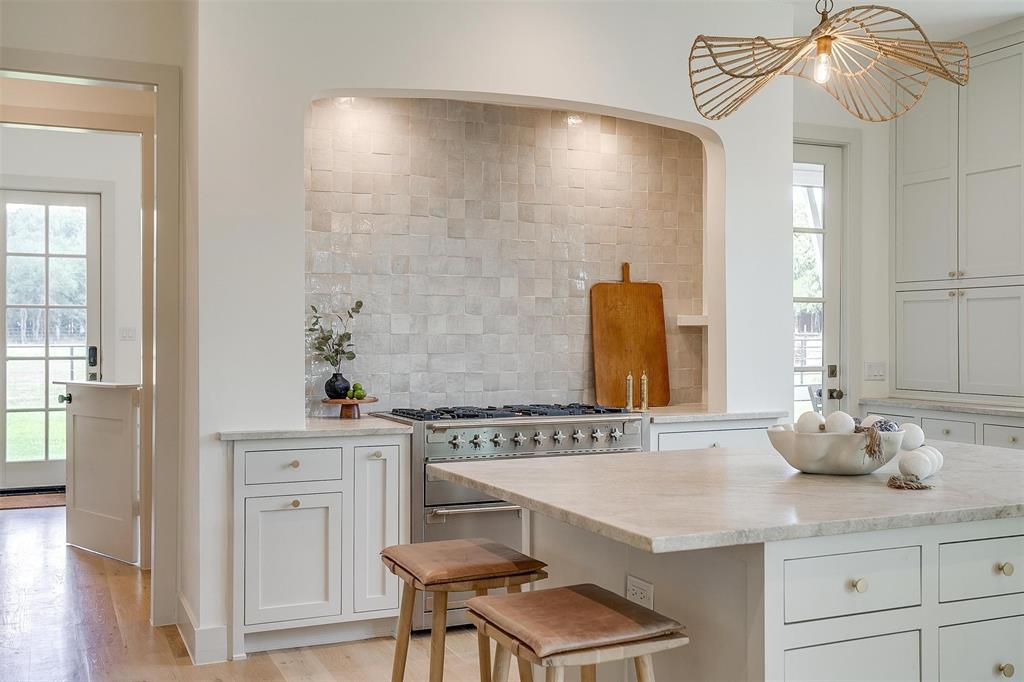 Hamptons-inspired elegance meets relaxed Texas living on this breathtaking 10± acre ag-exempt estate located just 18 miles from downtown Fort Worth in Aledo ISD. Behind 2 private gates, the property unfolds into a serene, tree-lined retreat with 2 beautifully designed residences, resort-style outdoor living, and thoughtful amenities at every turn. The 5,130± SF main home features 5 spacious bedrooms, 4.5 baths, and multiple living and entertaining spaces. A wall of glass upon entry offers a stunning view of the acreage beyond, while the chef’s kitchen delights with handcrafted Quartzite apron-front sinks, Aga appliances, and an oversized island with bar seating and an ice maker. Seamless transitions between indoor and outdoor spaces create the perfect backdrop for entertaining, whether gathered around the fireplace on the vaulted covered porch, relaxing on the screened-in porch, or soaking in the modern pool and spa surrounded by an AstroTurf yard and lounge seating. The 2,400± SF guest house offers incredible flexibility with a full kitchen downstairs, kitchenette upstairs, and 4 bedrooms—ideal as a pool house, private apartment, or guest quarters. A detached 285± SF studio offers the perfect space for an office, gym, or creative retreat. With four laundry rooms, two separate 2-car garages, wells and water filtration systems, and a buried propane tank, every detail has been designed with comfort and convenience in mind.  The property is cross-fenced and plumbed for livestock, with mature trees offering a peaceful, natural buffer at the back of the acreage. Gas lanterns flicker at sunset, front porch swings invite you to linger a little longer, and the sight of horses grazing in the distance brings a touch of timeless Texas charm. A rare opportunity to own a legacy estate where classic design and modern comforts exist in perfect harmony.