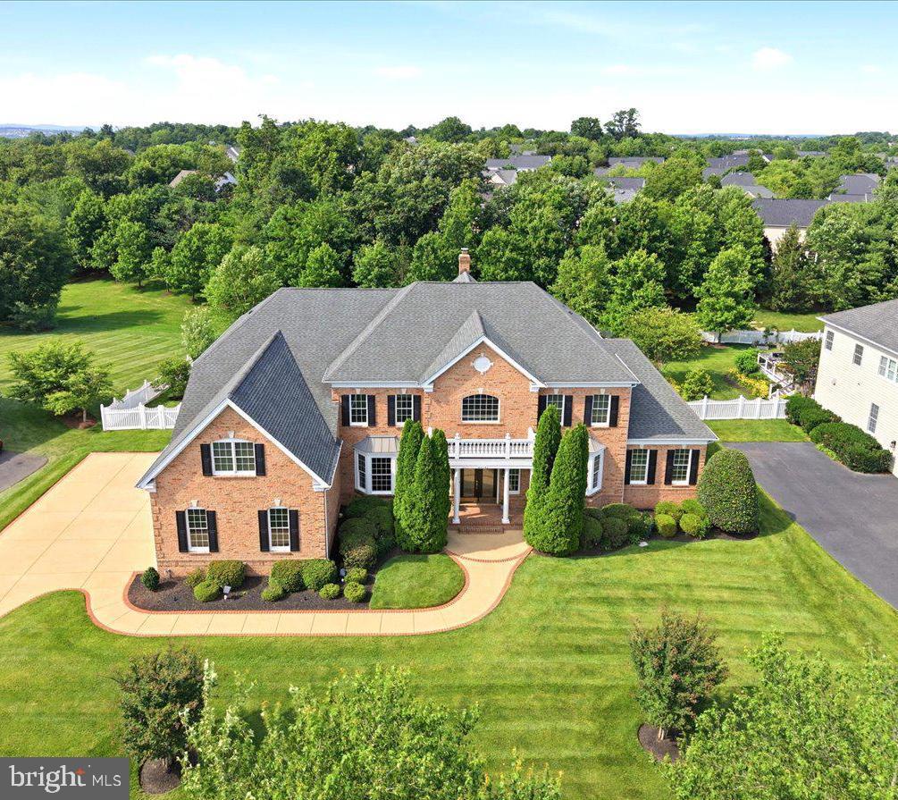 Welcome to an extraordinary Henley model estate in The Chase at Belmont Country Club, where timeless elegance, grand architecture and resort-style outdoor living create an exceptional lifestyle. Offering more than 8,000 square feet, this impressive residence features 4 upper-level bedrooms, 5 full baths, 2 half baths, a three-car garage, and a premium 0.57-acre lot backing to mature trees.A dramatic marble foyer makes a memorable first impression with a sweeping butterfly staircase, wrought-iron balusters, Juliet balconies, and a stunning chandelier with a motorized lift. Rich hardwood flooring, extensive millwork, tray ceilings, and designer finishes flow throughout the main level.Formal living and dining rooms provide elegant entertaining spaces, while a private study showcases custom wood bookcases, wood shutters, hardwood flooring, and a distinctive upholstered leather accent wall. The adjoining conservatory offers built-in shelving, custom shutters, and a wet bar with granite countertops and beverage refrigerator, creating the perfect library, lounge, game room, or music room.The gourmet kitchen is the heart of the home, featuring a 10-foot granite island, brand-new 72-inch Sub-Zero refrigerator, GE Profile stainless steel appliances, two Bosch dishwashers, abundant cherry cabinetry, walk-in pantry, and butler's pantry with sink. A spacious morning room provides flexible space for casual dining, hobbies, or gathering with family and friends.The backyard is truly spectacular, offering approximately 1,100 square feet of heated outdoor living space. A screened porch features a soaring wood-plank ceiling, exposed beams, wood-burning stone fireplace, television, custom surround sound, ceiling fans and radiant heaters for year-round enjoyment. The outdoor kitchen includes a full stone bar, sink, refrigerator, generous prep space, television, and gourmet gas grill with vent hood. Mature trees and fencing create a private, resort-like setting.Inside, the soaring two-story family room is filled with natural light from a wall of windows and features a coffered ceiling, fireplace, custom draperies, and a secondary staircase. Additional main-level conveniences include two powder rooms, a private mudroom entrance, and a spacious laundry room with utility sink.Upstairs, hardwood flooring continues through the gallery overlooking the foyer. Each bedroom features a private bath and generous closet space. The luxurious primary suite offers a tray ceiling, sitting room, spacious bath with dual vanities, jetted soaking tub, separate shower, dual water closets, two large walk-in closets, and a bonus room ideal for a fitness studio, dressing room, nursery, office, or private retreat.The finished walk-up lower level is designed for entertaining, featuring an expansive recreation room, custom wet bar with granite countertops, cabinetry, dishwasher, built-in beverage refrigerator, and full bath. Two exterior entrances provide direct backyard access, while large unfinished areas offer abundant storage and future expansion potential.Additional highlights include four HVAC systems, steam humidifier, two tankless water heaters, holiday lighting package, wired security system, twelve-zone irrigation system with new control panel, and an oversized three-car garage.Located outside the gates in The Chase, residents enjoy access to Belmont's coveted social membership amenities, including pools, dining, tennis, basketball, volleyball, soccer fields, playgrounds, fitness center, and an active social calendar. HOA dues include Comcast cable and high-speed internet.  An exceptional opportunity to own one of Loudoun County's most impressive luxury residences.