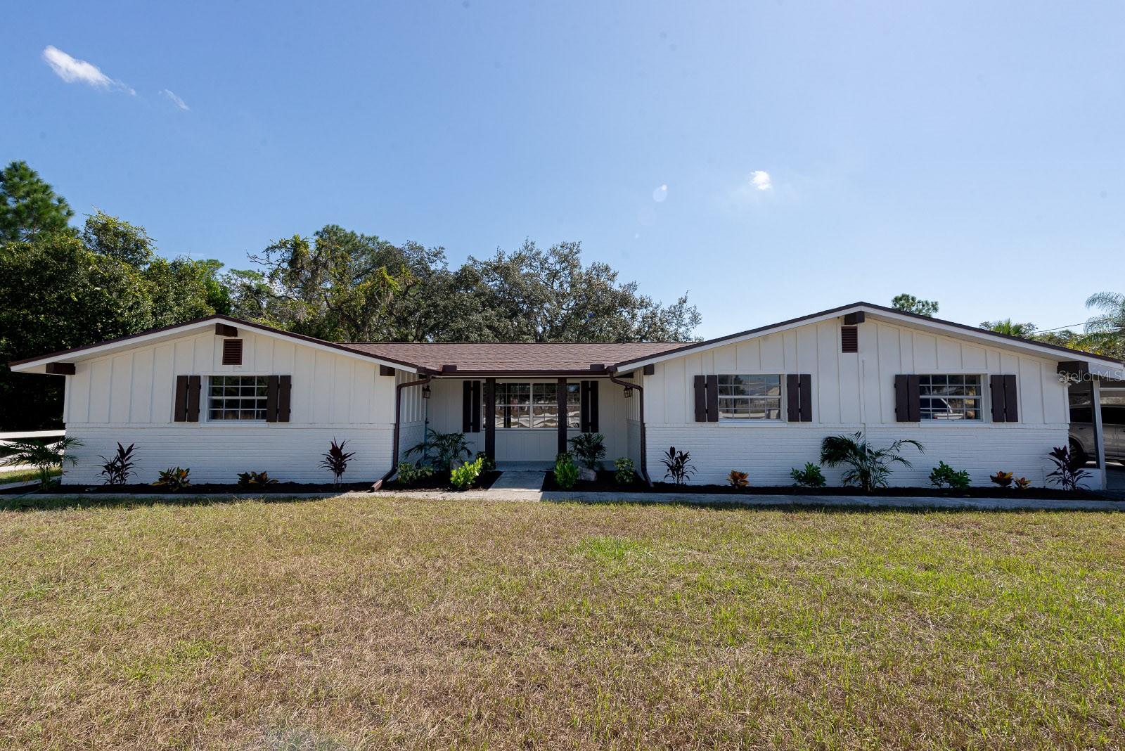 Opportunities like this don’t come along often! Welcome to this beautifully renovated country retreat, perfectly situated on a fully fenced 0.54-acre lot offering peace, privacy, and picturesque views of the horse farm in front and the tranquil pond behind. No HOA or CDD fees. From the moment you arrive, you’ll be captivated by this home’s fresh curb appeal featuring board-and-batten exterior siding, fresh paint, NEW ROOF , TWO NEW A/C UNITS with a 10 year parts and labor warranty, and an oversized two-car carport. Step inside to discover a spacious open-concept great room highlighted by French oak–style LVP flooring, recessed lighting, and an abundance of natural light. The chef’s kitchen has been completely transformed with 42-inch shaker cabinetry, soft-close drawers, gleaming quartz countertops, stainless steel appliances, recessed lighting, and an oversized island with generous seating—perfect for entertaining and everyday living. Just off the kitchen, the living and dining areas provide a seamless flow for gatherings. The primary suite offers a peaceful retreat with a walk-in closet and a fully renovated en-suite bath featuring marble-look tile floors, a new vanity, and a frameless glass walk-in shower. The secondary bedrooms are spacious and bright, and the updated second bath boasts a large vanity with quartz countertops. The expansive family room overlooks the backyard and pond, showcasing a charming wood-burning fireplace with custom board-and-batten surround, a custom mantle, and electrical for easy TV installation. French doors lead to a custom mudroom with built-ins—an ideal drop zone to keep the home organized. There is also lots of storage throughout the home. Enjoy outdoor living at its best on the large screened and covered patio, surrounded by mature oak trees and water views. A large shed with custom doors and covered storage provides the perfect space for lawn equipment, hobbies, or extra storage. This property is zoned 00ER, allowing general farming, livestock, and small animals (buyer to verify with county). Additional 2025 updates include a NEW SEPTIC TANK, DRAIN FIELD, WATER SOFTNER, FIXTURES, FANS, LIGHTING, HARDWARE, AND MORE.... All of this is conveniently located just minutes from the Suncoast Parkway (Tampa International Airport ~30 minutes), as well as top-rated schools, hospitals, shopping, dining, parks, beaches, and entertainment. This home is truly the perfect blend of modern comfort and peaceful country living—move-in ready and waiting for you!