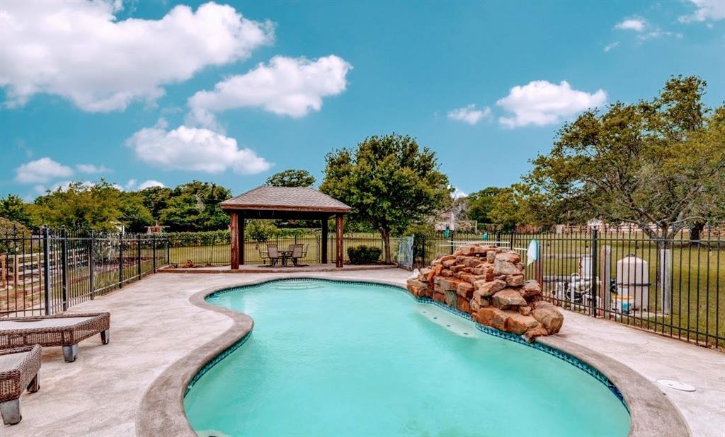 A highly sought-after N Keller home situated on a spacious 1.5+ acre lot, located on a tranquil cul-de-sac. Enjoy the tranquility of your private outdoor sanctuary, featuring a sparkling pool and an outdoor pavilion surrounded by mature trees. Upon entering, you are greeted by an open floorplan that merges elegance with functionality. A study with French doors is located off the foyer, leading to a spacious living room with views of the backyard and kitchen. The large kitchen is a chef’s delight, boasting custom cabinets and granite countertops. The family room and dining area feature a fireplace and luxury vinyl plank flooring. An oversized game room is perfect for entertaining, with a full bathroom nearby. Retreat to the expansive master bedroom and indulge in the ensuite, which includes a walk-in shower, freestanding soaking tub, a large closet, double sinks, and exquisite luxury. The office offers convenience for working from home. Additionally, there is a large utility room with a sink and an oversized detached garage. The property features a relaxing koi pond. An extra building with a garage door is situated at the back of the lot. Two horses are permitted.