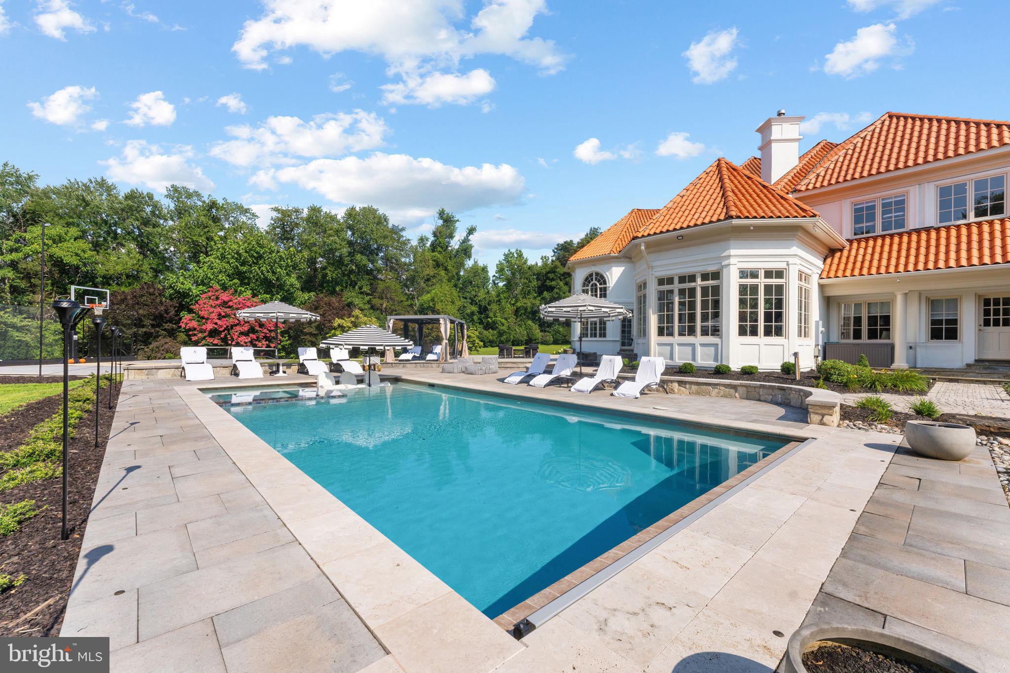 Gated 5.5-Acre Mediterranean Compound situated less than a mile from Great Falls Village with Rare 2.25% Assumable Financing. This extensively renovated villa stands as a private resort along Northern Virginia’s most coveted luxury corridor. Designed for seamless multi-generational living and effortless hosting on a grand scale, this residence blends architectural prestige with absolute tranquility.Inside, an expansive open floor plan creates a fluid transition between light-filled spaces. The impressive family room commands attention with floor-to-ceiling windows and a soaring stone fireplace, framing panoramic views of the verdant grounds. At the center of the home, a state-of-the-art chef’s kitchen serves as a culinary showcase, complete with top-of-the-line Miele appliances, a café-style gas range, custom cabinetry, and polished quartz countertops. The main level thoughtfully integrates formal reception rooms, a custom mudroom, a sunlit four-season conservatory, and a serene primary suite.The upper level acts as a private wing, featuring a second lavish primary suite alongside four additional en-suite bedrooms, each outfitted with custom walk-in closets and redesigned spa bathrooms boasting full-slab marble showers and designer vanities. Downstairs, the walk-out lower level serves as an ultimate wellness and leisure haven, offering a private cinema, an expansive recreation lounge, a full bath, and a dedicated fitness facility that easily converts into a seventh bedroom suite.Outdoors, the estate reveals its true resort identity with a heated saltwater swimming pool, a newly constructed regulation basketball court, a peaceful private pond, and expansive flagstone terraces crafted for alfresco dining. Guests arrive via a sweeping circular driveway capable of holding over 25 vehicles, anchored by a three-car garage. Major upgrades include six new HVAC systems, new roof insulation, a newly paved driveway, and a partial generator. Call to schedule a private tour today! Square footage is deemed reliable but not guaranteed.