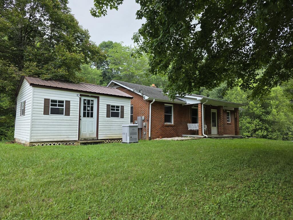 This brick ranch offers 3 BR, 2 BA, and a full basement. The 1,008 sq. ft. main level includes a living room, kitchen, dining area, 2 BR, full BA, and laundry room. The full basement adds a third BR, second full BA, woodstove, and unfinished space for storage or expansion. Situated on +/-2.11 acres atop a hill, the property features Big Indian Creek across the road and the West Fork of Big Indian Creek along the rear boundary. Includes hardwood and vinyl flooring, electric baseboard heat, covered front porch, rear deck, storage building, additional outbuildings, spacious yard, private country views & soothing creek sound