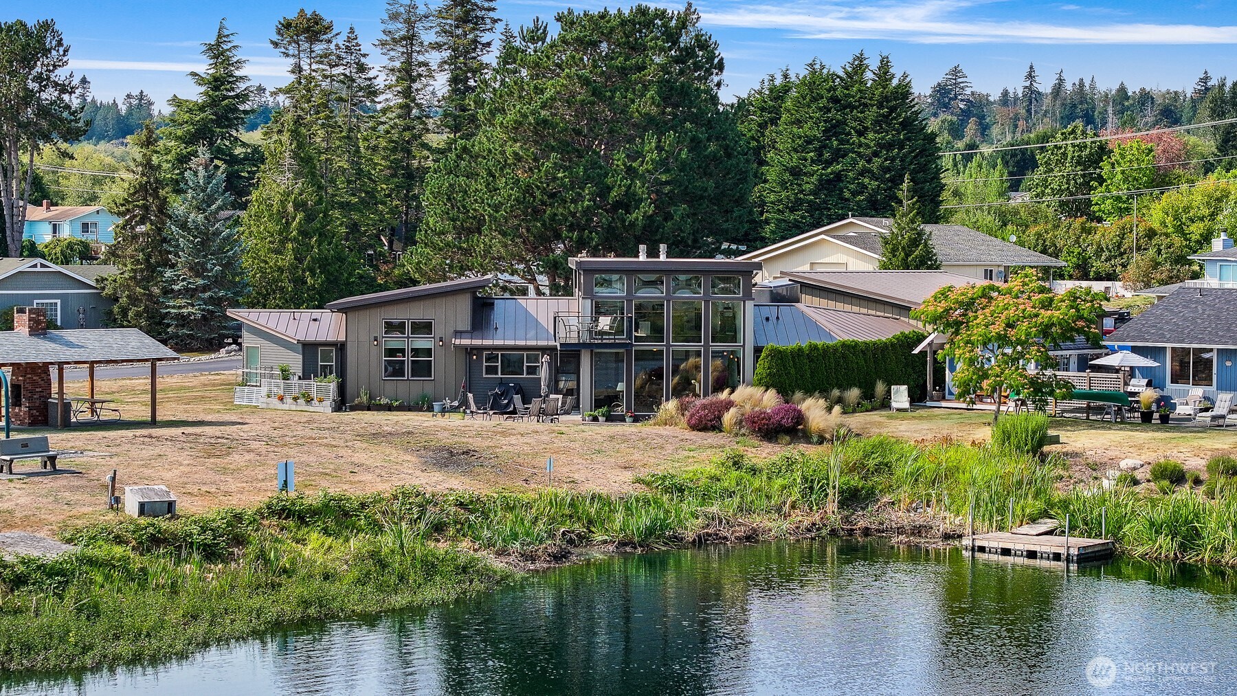 Modern Northwest living meets an exceptional Birch Bay Village setting. Set on a sunny corner lot along the golf course, this distinctive 2,997-sq-ft contemporary home captures sweeping open green space, lake, and mountain views. A dramatic wall of double-paned windows fills the soaring great room with natural light, bringing the scenery indoors. Warm wood accents, a gas fireplace, and soaring architecture create an inviting atmosphere for everyday living or entertaining. This chef-inspired kitchen features abundant cabinetry, quality appliances, generous prep space, a large island, and a walk-in pantry. The French doors open to the patio, extending living outdoors for dining, relaxing, or taking in the peaceful surroundings. Upstairs, a light-filled loft overlooking the great room offers an inspiring office, media room, or retreat. Step onto the private balcony to enjoy beautiful Northwest sunsets. All 3 bedrooms are conveniently located on the main floor, including a spacious primary suite with a walk-in closet and ensuite bath. Radiant heat, generator wiring, attached 3-car garage plus RV parking provide comfort and versatility. Within gated Birch Bay Village, enjoy golf, private beach/water access, marina/boat launch, clubhouse, parks, playground, and much more. Minutes from Birch Bay and Semiahmoo, this is more than a home; it’s a place to relax, entertain, connect, and embrace the Northwest lifestyle every day.