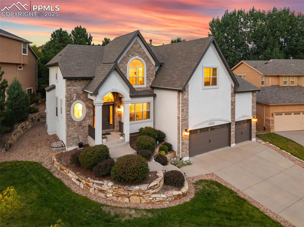 Welcome to this stunning 6-bedroom, 5-bathroom home with over 4,500 sq ft and a spacious 3-car oversized garage, perfectly situated in the highly desirable Stone Crossing neighborhood. Surrounded by community amenities including an outdoor amphitheater, scenic pond, and trails, this home offers a true Colorado lifestyle near schools, shopping, and the Air Force Academy. The beautifully manicured front yard and covered porch invite you inside, where hardwood floors and a vaulted ceiling create a grand entrance accented by modern lighting. The formal dining room is ideal for family gatherings. Adjacent, the formal living room offers a cozy tile fireplace and plush carpet, creating the perfect space to unwind or entertain. A convenient powder room with tile counters and storage is just steps away. Continue into the hearth room with hardwood floors, stone fireplace, and custom built-ins. The gourmet kitchen boasts granite countertops, hardwood flooring, stainless sink, gas cooktop, walk-in pantry with wood shelving, appliance storage closet, and a large eat-in island. The breakfast nook opens to a spacious deck, with mature trees lining the backyard. Upstairs, the luxurious primary suite offers a sitting area, tile fireplace, 5-piece bath with soaking tub, and a generous walk-in closet with center island. The second bedroom has an en-suite full bath, while the third and fourth bedrooms share a Jack-and-Jill bath with private vanities, walk-in closets, and Pikes Peak views. The finished basement includes two additional bedrooms, a bathroom with a shower, a large family room with slate fireplace, and a wet bar with granite counters, copper sink, wine cooler, and beverage fridge. The dedicated theater room features six plush chairs for a cozy viewing experience. With access to District 20 schools, proximity to the Air Force Academy, this home is ideally located!