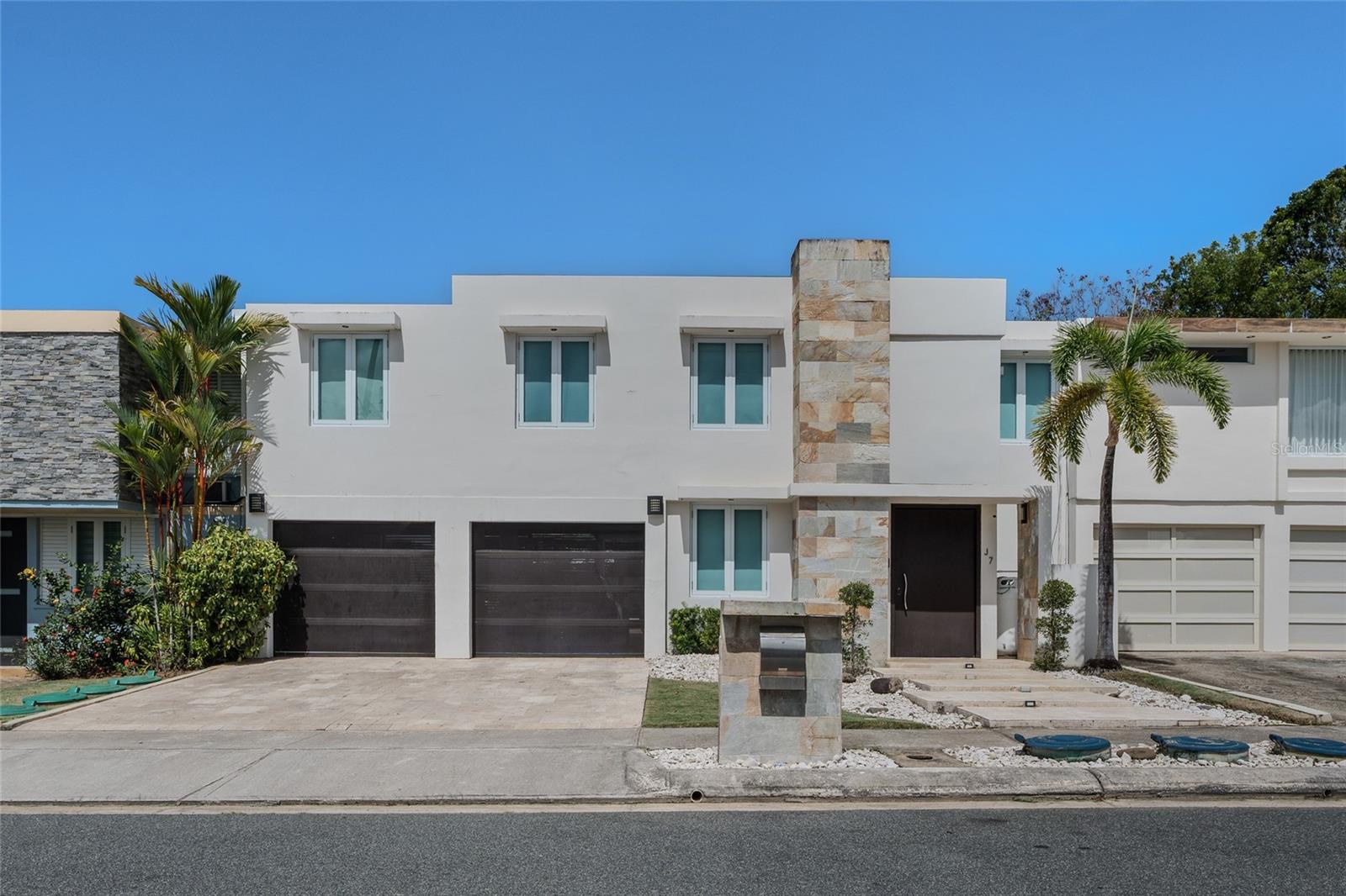Beautifully updated two-story residence in the desirable gated community of Prado Alto, Guaynabo, featuring a sophisticated contemporary design and thoughtfully designed indoor and outdoor spaces. The home offers approximately 2,462 sq. ft. of living area, with elegant marble flooring, custom wood accents, modern lighting, an open staircase, and bright, spacious living and dining areas.The remodeled kitchen features sleek cabinetry, quartz-style countertops, generous storage, and a breakfast area. The primary suite offers a spacious layout with a modern en-suite bathroom, while the home also includes a dedicated laundry room. The private backyard is designed for entertaining and relaxation, featuring a pool, landscaped patio, covered wood pergola, and outdoor dining area. The contemporary façade, stone accents, and two-car parking complete the home's modern aesthetic. Conveniently located in Guaynabo with easy access to schools, shopping, restaurants, and major highways, this move-in-ready property combines contemporary style, comfort, and an excellent location.