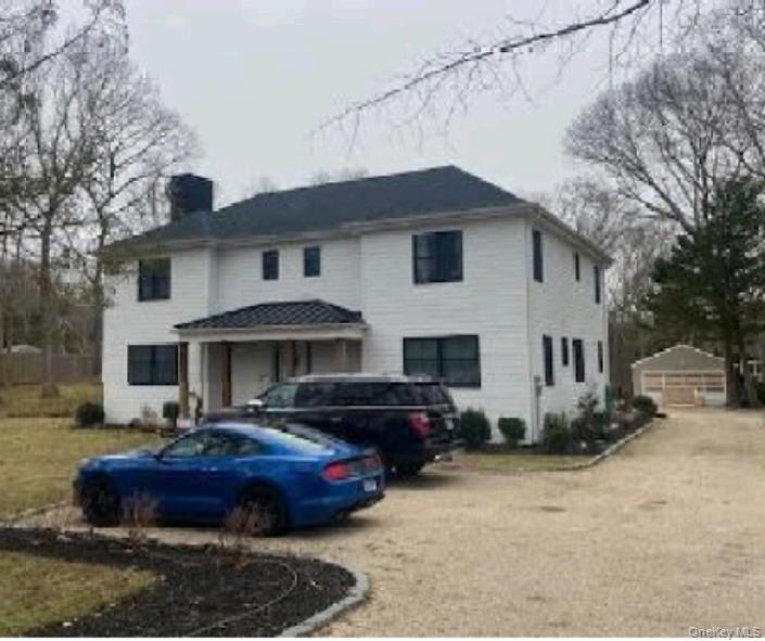 Spacious post-modern home offering approximately 3,080 sq ft of living space on a shy acre in Hampton Bays. Interior highlights include an eat-in kitchen, living and dining areas, a first-floor bedroom with full bath, and a covered rear porch. The second level features a primary suite with en-suite bath, additional bedrooms, a full bath, and a dedicated laundry room. Full unfinished basement with exterior access and a detached two-car garage. Conveniently located north of Montauk Highway near parks and bay access.