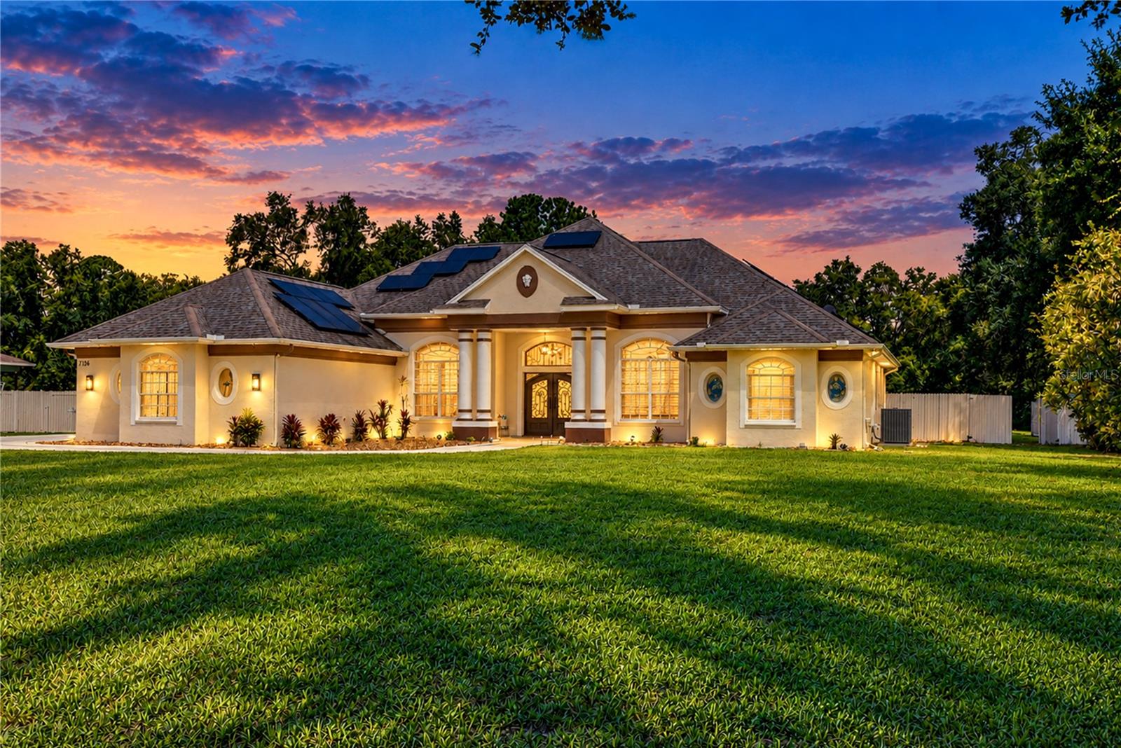 Spacious, energy-efficient and packed with features, this 3-bedroom, 2-bath home offers an impressive 2,692 heated sq ft plus exceptional indoor and outdoor living. High ceilings, extensive crown molding and 24"x48" Italian porcelain tile set the stage inside. The well-appointed kitchen features quartz countertops and backsplash, raised-panel cabinetry, glass cooktop, built-in oven and microwave, stainless steel appliances, pull-out pantry and breakfast bar. Multiple living and dining spaces provide plenty of room to spread out, while the split-bedroom layout offers added privacy. The primary suite features bay windows, dual closets with built-in storage and an impressive ensuite with an oversized glass shower, dual shower heads, bench seating, separate vanities, vessel sink, private water closet and thoughtful tile details. Additional bedrooms also feature built-in closet storage. Outside is where this property truly stands apart. Enjoy a large free-form, solar-heated pool and spillover spa with rock feature and pebble finish, all within an expansive screened lanai featuring programmable LED lighting. The property is fully fenced with multiple gated areas and includes a 2-car garage, extended driveway/parking pad and an approximately 30'x40' covered RV area equipped with 220V electric, currently accommodating a 40-foot fifth wheel. An extensive 72-panel solar system supports major electrical demands including the A/C, heated pool, Tesla charging and RV use. Despite these demands, the seller reports an average electric bill of approximately $40/month based on current usage and utility history. Additional features include hurricane shutters, well and septic, newer well PVC piping, water softener, security camera/alarm system and an additional fenced rear portion of the property offering extra privacy, storage and flexibility. Subject to applicable zoning and permitting, the additional space and covered structure may provide possibilities for future permitted uses. This is far more than a traditional 3/2, it's a property designed for space, entertaining, RV living, energy efficiency and flexibility.