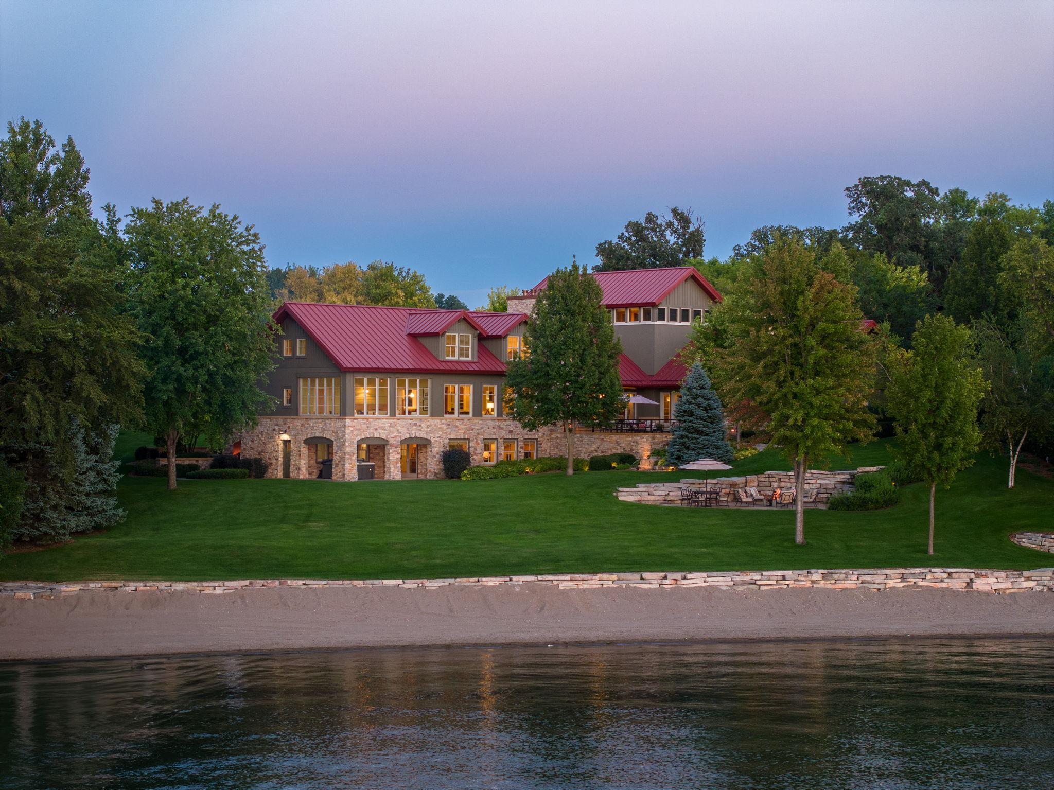 Beyond the custom iron gates, escape to paradise in this stunning 12,211 square foot custom waterfront retreat on 30 acres with 200 feet of private sandy beach. Designed by award-winning architect Rehkamp Larson, this contemporary masterpiece boasts three extraordinary stories with floor-to-ceiling walls of glass offering breathtaking lake panoramas from every room. Inside, fall in love with the unparalleled craftsmanship featuring 6 enormous bedrooms including a main level primary suite, 7 bathrooms, a private bell tower office, library, and sunroom with bi-folding doors to connect you with nature. Entertain in the state-of-the-art kitchen that includes top-of-the-line appliances such as a Sub Zero, Wolf, and Miele. Unwind in the cinema, workout in the gym, or relax in your preference sauna or steam room. Unwind in the jacuzzi, just off the lower-level billiards room. Enjoy the 3,305 sqft. four garage guest house for storing of your motorized vehicles used to explore the 30+ acres.