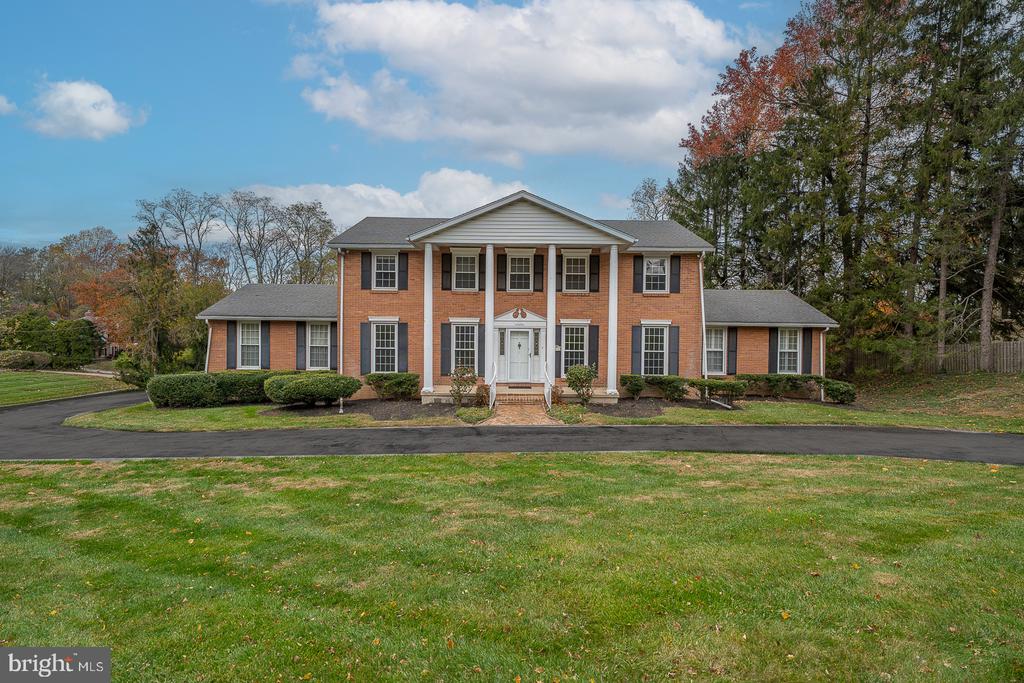 Welcome to this stately and spacious residence nestled on a beautifully landscaped 0.83-acre lot in one of Gladwyne’s most desirable neighborhoods. Offering 6 bedrooms, 4 full bathrooms, and 1 half bathroom, this home combines classic charm with modern comfort in the award-winning Lower Merion School District. A circular driveway leads to the stately front entrance, framed by timeless two-story pillars. The center hall opens to a grand formal living room featuring detailed crown molding and a double-sided gas fireplace, which also warms the covered rear porch—perfect for relaxing or entertaining. The sun-filled formal dining room with hardwood floors and built-in cabinetry sits conveniently adjacent to the kitchen for seamless entertaining. The kitchen boasts stainless steel appliances, a breakfast bar, and opens to a bright family/sunroom enhanced by skylights and sliding glass doors overlooking the tranquil backyard. The main-floor primary suite features a spacious walk-in closet with laundry and a full ensuite bath. Upstairs, a second primary suite includes its own walk-in closet and private bathroom. Three additional bedrooms with generous closets and a full hall bath with laundry complete the upper level. The finished walkout lower level offers additional living space, including a bedroom with ensuite bath and walk-in closet—ideal for guests or an au pair suite—along with a large recreation room with gas fireplace and access to the back patio and yard. Additional highlights include an oversized two-car garage, lush landscaping, and an unbeatable location close to the Philadelphia Country Club, major roadways, and all the dining and shopping in Gladwyne and nearby Conshohocken.