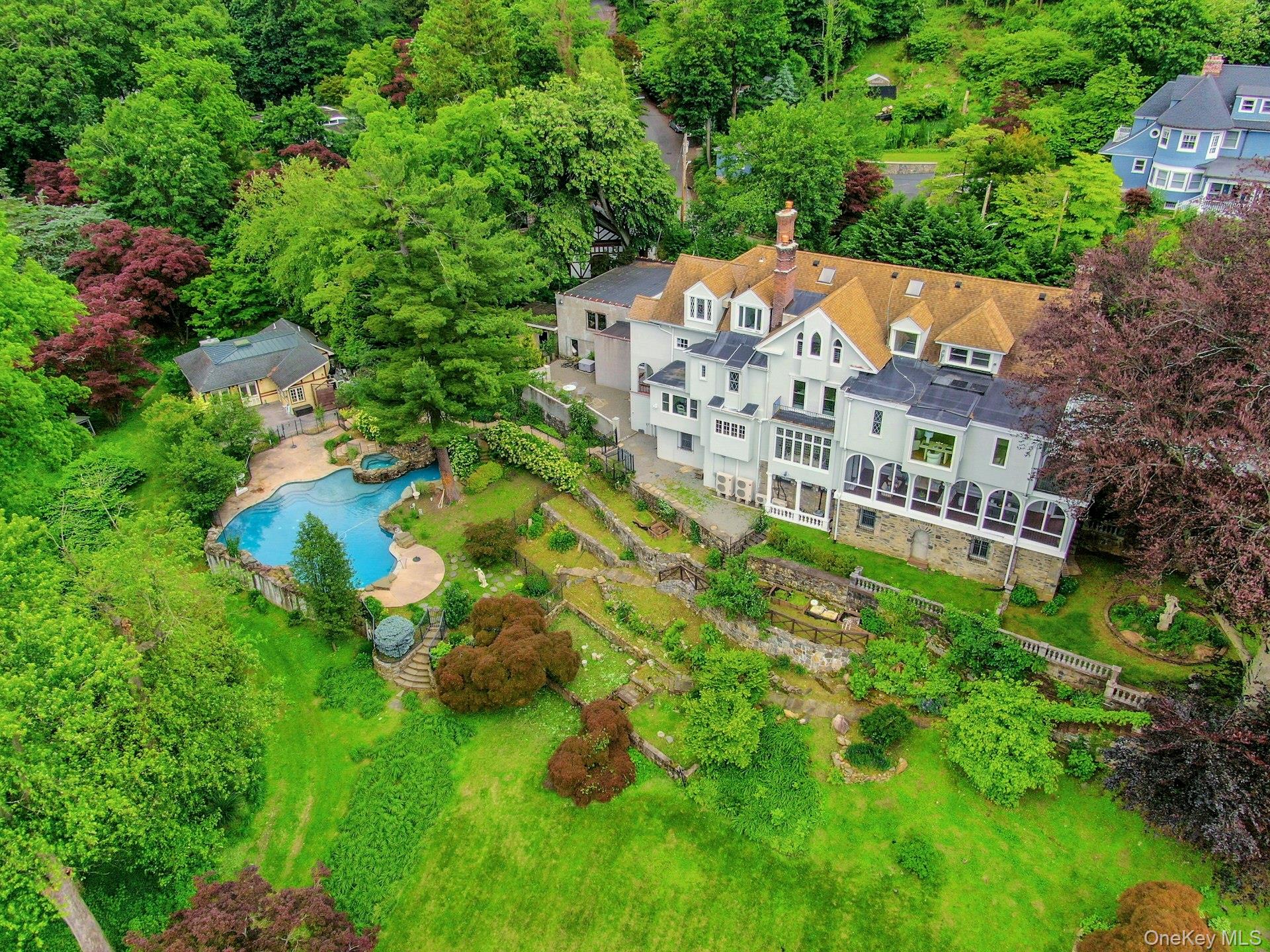 Perched above the Hudson River on 3.5 gated acres in the heart of Tarrytown is a stunning
home historically known as “Whitehall.” Built in 1929, this grand residence offers sweeping,
unobstructed views of the river and Mario Cuomo Bridge—and all the timeless charm of a
European manor, just 36 minutes from Grand Central.
The property is a world unto itself: a fenced-in pool and hot tub with an expansive deck and pool
house (complete with full eat-in kitchen, outdoor and steam showers, and rec room); a private
tennis court with basketball hoop; a tranquil pond Monet would have loved to paint; and stone
staircases that wind through hidden alcoves and secret gardens. Stone sculptures and layered
landscaping add a sense of magic and discovery, giving the feeling you’ve stepped into another
era—or another country.
The 9-bedroom, 3.5-bath main house is full of character: original stained glass, rich wood
paneling, wrought iron railings, hidden doors, a basement safe built to store furs, and other
vintage details throughout. The kitchen has been recently renovated, and new carpeting and
flooring run through much of the home—including a fully refreshed top floor.
Multiple entertaining spaces offer flow and flexibility, including a full butler’s pantry, breakfast
nook, formal dining room, and a massive screened-in porch perfect for enjoying the views in any
weather. The primary suite includes a large bathroom, walk-in closet, sitting room, and its own
Juliet balcony. Upstairs laundry, a 3-car garage, and a large driveway provide modern
convenience, while the home’s storied layout and architectural details make it truly one of a
kind.
The home sits right next to the Old Croton Aqueduct, a historic, tree-lined trail that stretches
from the Bronx to the Croton Dam—perfect for walking, running, biking, and enjoying nature
year-round. It’s also steps from Patriots Park, home to many local events, including the award-
winning TaSH Farmers Market. In the other direction, you’re a short walk from Wilson Park and
the trails surrounding the Tarrytown Lakes.
Whitehall is more than a home—it’s a destination. A timeless estate with iconic views and
endless potential, just moments from the villages of Tarrytown and Sleepy Hollow and less than
an hour from New York City.
Includes: Generator