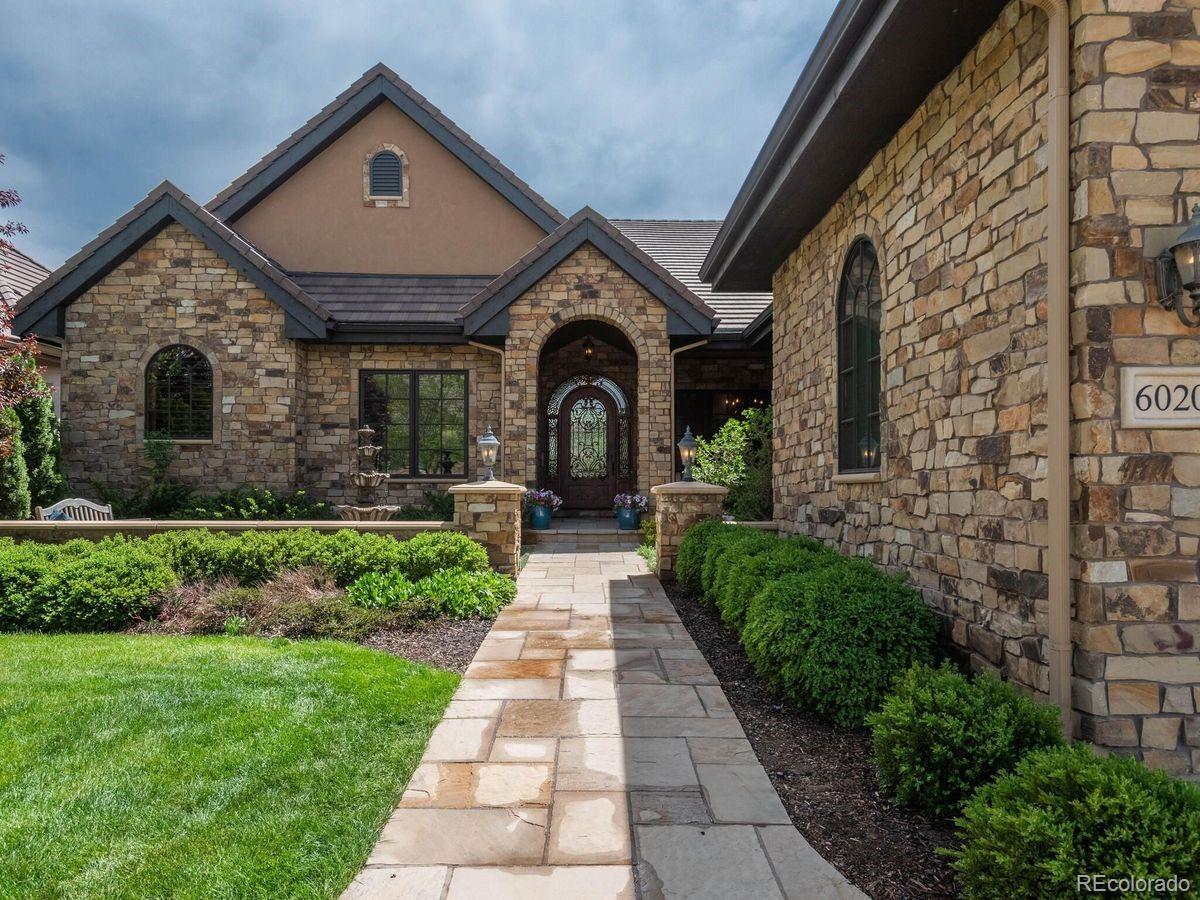 Set within a private, gated enclave, this custom home offers refined living defined by privacy, tranquility, and the highest quality of craftsmanship. One of only four residences in the community that backs directly to the peaceful High Line Canal Trail and protected open space beyond, its setting delivers the feeling of an acreage estate—with virtually none of the maintenance. Entering through the custom iron front door, floor-to-ceiling windows in the great room frame beautiful views of the open space beyond, filling the interiors with natural light. The thoughtfully designed open floor plan creates a seamless connection between indoor and outdoor living, making the home equally suited for intimate evenings and effortless entertaining. The open-concept kitchen anchors the home with furniture-style raised-panel cabinetry; Sub-Zero, Wolf, and GE Monogram appliances; a hand-carved stone vent hood, and generous island seating. Glass doors extend the living experience outdoors to an expansive covered living space with a gas fireplace, built-in grill, speakers, and ceiling fans, creating a true year-round retreat ideal for gathering by the fire or enjoying dinners al fresco. With all primary living spaces—including the primary suite and laundry—conveniently located on the main level, the home offers exceptional ease of daily living and long-term comfort. The finished walkout lower level is filled with natural light and opens to a private lower patio featuring a hot tub and gas fireplace—perfect for hosting guests or unwinding in complete privacy. Throughout the home, luxury finishes include vaulted ceilings, lightly hand-troweled walls, solid-core 8-foot knotty alder doors, radiant-heated stone floors, and custom millwork. A professionally installed Control4 system integrates lighting, audio, and entertainment, while the association provides exterior maintenance, landscaping, snow removal, and trash service—delivering a true lock-and-leave lifestyle without compromise.