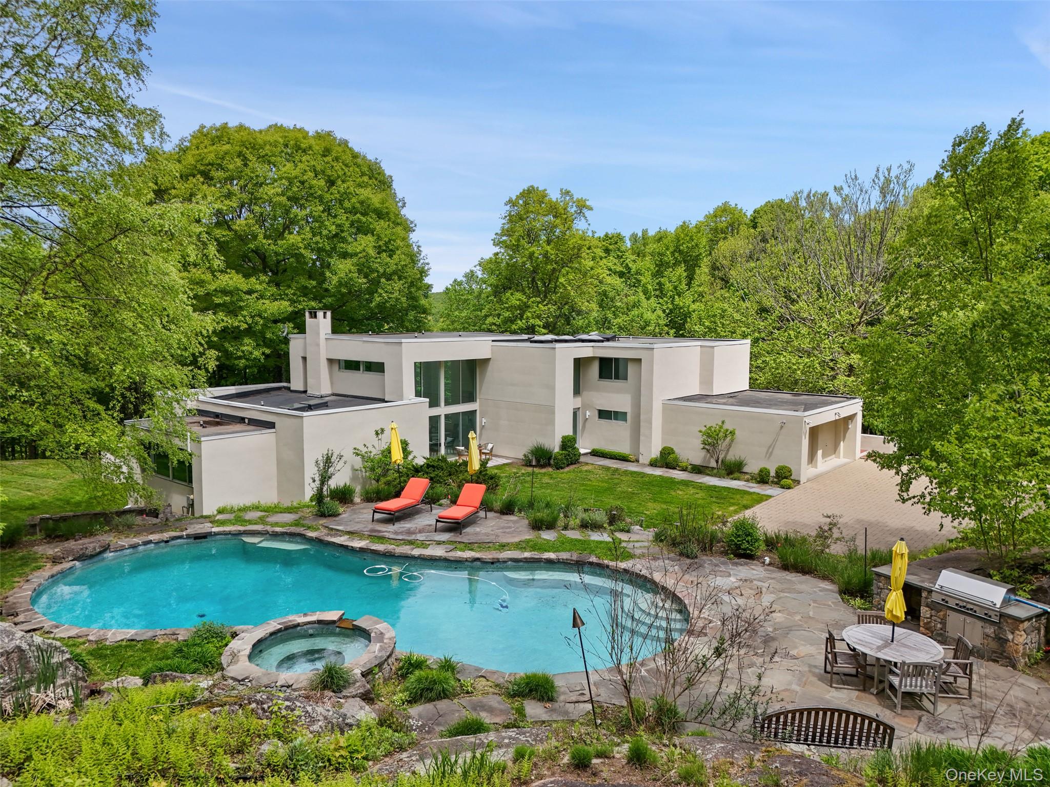 Set high on a hill overlooking the Pound Ridge Reservation, 71 Old Stone Hill Road is a dramatic Modern positioned to capture natural light and distant views.  Constructed in 1987 housing approximately 4420 square feet of living space, the interior is stunning.  The floorplan is open and fluid allowing for seamless entertaining.  Clean, crisp lines, walls of windows, high ceilings, lots of glass, hardwood floors, a fireplace and     custom built-ins.  Doors open to two terraces, perfect for indoor/outdoor entertaining.  Living Room - a dramatic space with soaring ceiling, walls of glass, clerestories usher in natural light & views. Dining Area with custom built-ins, open to Living Room & Entry.  Kitchen with Breakfast Area with access to outdoor Terrace.  First Floor Primary Bedroom with doors out & Primary Bath.  Second Floor offers Two Bedrooms sharing a skylit Bathroom an additional Fourth Bedroom with private Bath.   Comprised of approximately 3.3 acres, the grounds are beautifully landscaped with mature trees, level lawns & dramatic outcropping.  A free-form Swimming Pool offers a private refuge.  While quiet & private, the property is conveniently located, just moments from town park, local schools, shops & restaurants of Scotts Corners & Bedford Village.