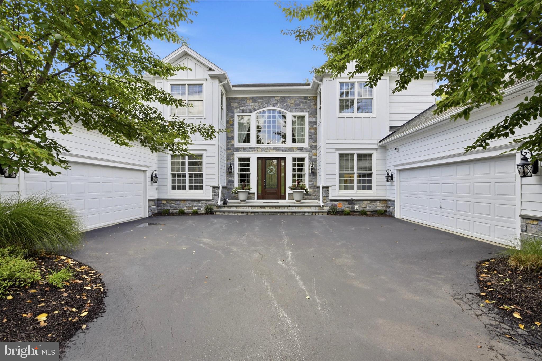 Welcome to 1476 East Stonington Drive, situated in the highly sought-after Reserve at Chestnut Ridge and within the award-winning Downingtown Area School District. This home combines timeless elegance, expansive living spaces, entertaining areas, and extensive recent improvements. The exterior features a stately front porch, limestone paver entry, courtyard-style garages, mature landscaping, and a wooded rear setting. Inside, the grand two-story foyer showcases hardwood floors, a double spiral staircase, wainscoting, crown molding, designer sconces, chandelier, palladium windows, and coat closets. A private au pair/in-law suite is located off the foyer and includes a walk-in closet and updated full bath with Carrera marble flooring, quartz vanity, subway-tiled shower, and custom tile inlay. The main level is ideal for everyday living and entertaining. The sun-filled dining room features a soaring two-story ceiling, wainscoting, crown molding, picture window, and recessed lighting. The gourmet eat-in kitchen offers abundant 42-inch cabinetry, under-cabinet lighting, granite countertops, a double-stacked granite island with seating, custom tiled backsplash with decorative inlay, stainless steel appliances, recessed lighting, walk-in pantry, and breakfast area. The breakfast area opens to a Trex deck overlooking the wooded rear setting. The spacious family room features a wood-burning fireplace, crown molding, recessed lighting, built-in surround sound speakers, windows, and access to a second private Trex deck. A formal living room provides additional entertaining space, while the private office/study with French doors is ideal for working from home. An updated powder room, laundry room, and tiled two-car garage complete the first floor. The renovated laundry room includes custom cabinetry, tile flooring, quartz countertops, and stainless-steel sink. Upstairs, a landing/seating area leads to the primary suite with French doors, decorative pillars, private sitting area, and his-and-her double walk-in closets with custom built-ins. The recently updated spa-inspired primary bath features custom tiled flooring, soaking tub, dual granite vanities, makeup station, stone backsplash, crown molding, and oversized tiled shower with dual shower heads. Three additional bedrooms each offer access to recently renovated full tiled bathrooms. The finished lower level expands the home's living and entertaining space with new hardwood flooring, recessed lighting, chair rail detail, surround sound, and walk-out access to the rear yard. A Dimplex fireplace with porcelain hearth serves as a focal point, while the custom wet bar features granite countertop, built-in cabinetry, wine fridge, and kegerator. A full tiled bathroom with quartz vanity adds versatility. The lower level also includes a fitness room with laminate hardwood flooring, recessed lighting, mirrors, and a large storage room with shelving. Additional highlights include plantation shutters in the family and living rooms and a second two-car garage accessible from the exterior. Extensive improvements were completed throughout 2025 and early 2026, building upon previous renovations including updated tiled bathrooms and fixtures, carpeting, kitchen countertops, backsplash and appliances, fitness room, stucco removal, James Hardie board-and-batten siding with stone façade, limestone paver front porch, front door, select windows, and replacement heating and air-conditioning systems. Outside, the rear yard backs to a peaceful wooded setting filled with mature trees. Two Trex decks provide opportunities for outdoor dining, entertaining, and relaxing. Ideally located near major routes, shopping, dining, entertainment, and everyday conveniences. 1476 East Stonington Drive offers an exceptional combination of luxury, privacy, space, and extensive recent improvements. This remarkable home is ready to welcome its next owner. Be sure to Schedule your private tour today!