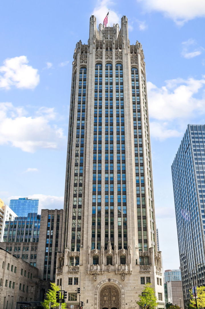 A rare opportunity at Tribune Tower - one of only a few homes on the fourth floor, offering true 12-foot ceilings and the kind of vertical volume that transforms the feel of every room.    This 1,440-square-foot, one-bedroom, one-and-a-half-bath residence is one of the select few with a private balcony overlooking the building's landscaped courtyard - a quiet, green centerpiece in the middle of the city.    The interiors are understated and lasting: wide-plank hardwood floors, a clean material palette, and Lutron electronic window treatments throughout. The kitchen is finished with quartzite countertops, custom cabinetry, and a full suite of Miele, Wolf, and Sub-Zero appliances.    The primary suite offers two massive walk-in closets and a spa-caliber bathroom wrapped in Carrara marble - complete with soaking tub, large walk-in shower, double vanities, and fixtures by Waterworks and Kohler.  Tribune Tower residents enjoy access to over 55,000 square feet of amenities, including a 75-foot indoor/outdoor pool, sun deck with Wolf grills, fitness center, golf simulator, and a well-appointed lounge with billiards and darts. The Crown Terrace on the 25th floor delivers panoramic skyline views from one of the most iconic rooftops in the city.
