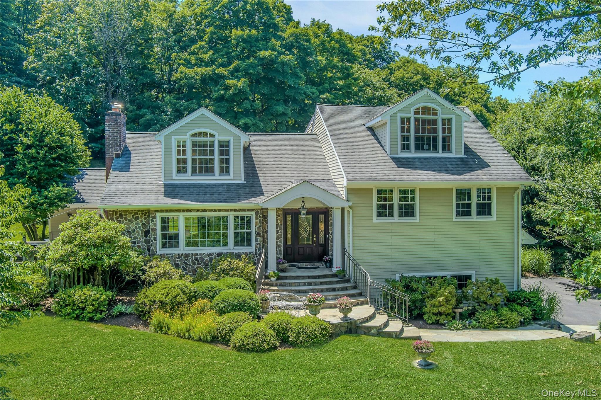 Perched on a lushly landscaped acre and thoughtfully expanded, offering a comforting blend of function, space, and versatility for today’s lifestyle, whether working from home (the main-level office opens to a private deck, creating a delightful setting for morning coffee or an inspiring workday), entertaining (the spacious living room with fireplace adjoins the formal dining room with sliding glass door to the patio for easy alfresco dining; the bright eat-in kitchen is smartly designed with custom cabinetry and granite countertops, and a breakfast area with a big bay window and a French door to the patio for immediate access to outdoor cooking and entertaining), or simply enjoying room to spread out (an expanded family room, den/study/playroom/home office x 3, 3 spacious bedrooms, 4 full bathrooms [including 2 ensuite]), there’s a place for everyone to live, work and play. Versatility abounds in the expanded family room with its built-ins and spaces to recreate, work or relax. The luxurious primary suite features a soaring ceiling, oversized windows, boutique-like walk-in closet, and a spa-like bath with double vanity, soaking tub, and separate shower. The second bedroom also features a walk-in closet and an upscale, private ensuite bath with shower. The shared hall bath has been recently refreshed with a double vanity, sconces and mirrors, plus new tile and glass surrounding a bathtub with shower and handheld. The lower-level playroom enjoys easy indoor/outdoor access with a French door to the yard. Commandingly set on a pretty, landscaped acre with a large patio and terraced lawns adding to the scenic surroundings. Welcoming, comforting, spacious and versatile inside and out.