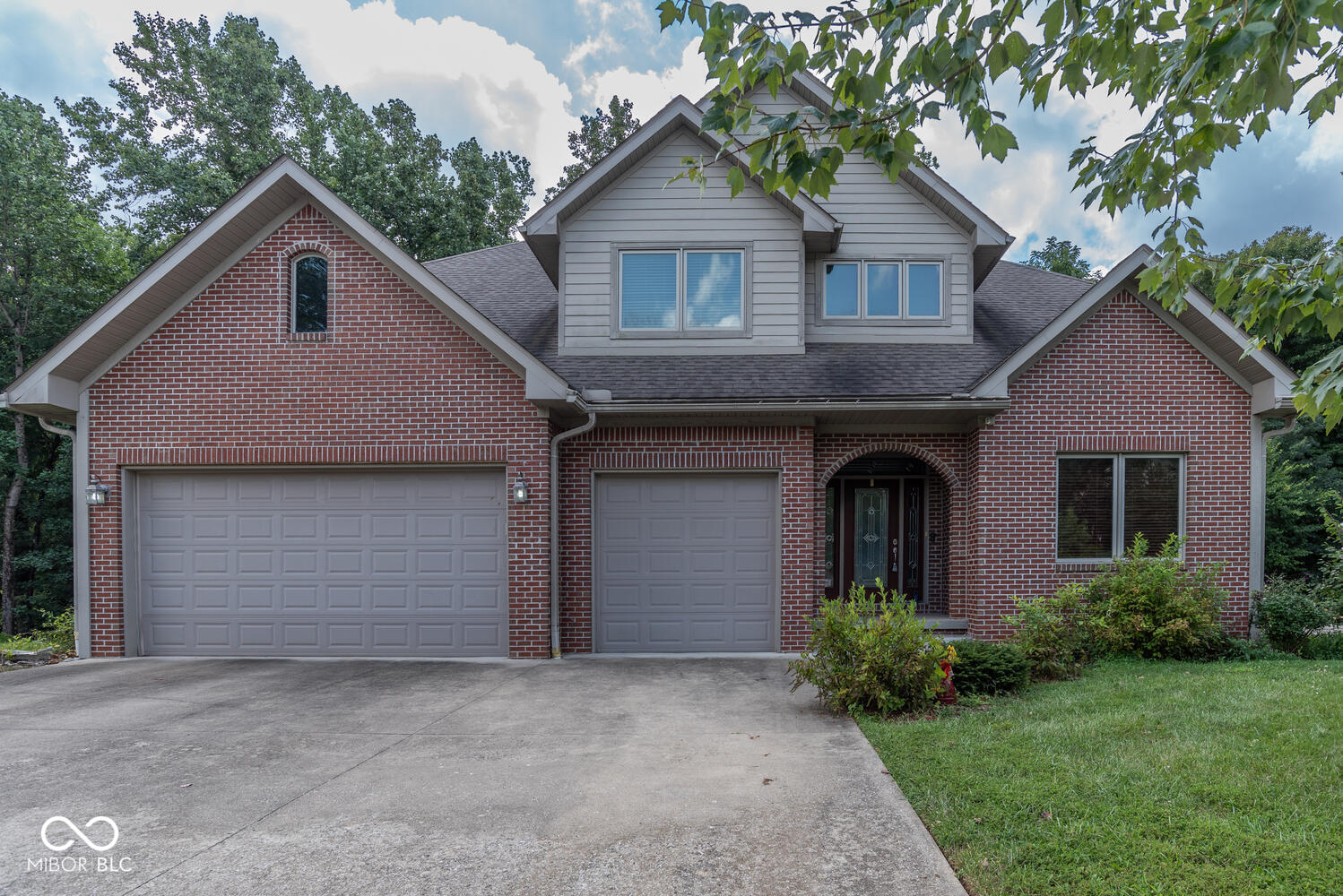 Convenient to IU & the entire east side, this quality 11/2-story residence was designed with timeless elegance, modern convenience, and an exceptional setting the includes a wooded nature conservancy as your back yard neighbor!  The striking foyer opens to soaring ceilings & shiny hardwood floors. The inviting great room with a vaulted ceiling, plenty of natural light, a cozy gas log fireplace, & beautiful leaded glass double doors leads to an expansive deck overlooking the secluded, tree-lined backyard.  The fabulous kitchen is the heart of the home & features gorgeous custom cabinetry, granite countertops, beautiful appliances, a prep/veggie sink, & abundant counter & cabinet space. Ceramic tile adds durability & style in the kitchen, baths, & laundry. A convenient mud/laundry room offers custom cabinetry & a laundry sink.The main-level primary suite is a true retreat with hardwood flooring, a spa-like en suite bath boasting a glass and marble shower, soaking tub, transom window for natural light, double vanity & a custom walk-in closet with built-in organization system. Upstairs, a large loft provides flex space surrounded by 3 bedrooms & a full bath-including one bedroom with its own private en suite bath.  The finished walk-out lower level expands the living space with an open recreation area featuring laminate flooring, a full bath, screened porch, & walk-out access to the fenced backyard. A workshop & dedicated storage area complete the lower level. With its combination of thoughtful design, premium finishes, & peaceful wooded views, this home offers the perfect balance of luxury & comfort.  Highlights include a 11/2-story design with primary suite on main level; 5 bedrooms & 4.5 Baths; a deck, covered patio & screened porch for outdoor living;  3-car garage, workshop, and ample storage; secluded backyard with privacy fence & nature conservancy views! The home blends architectural interest with everyday livability.