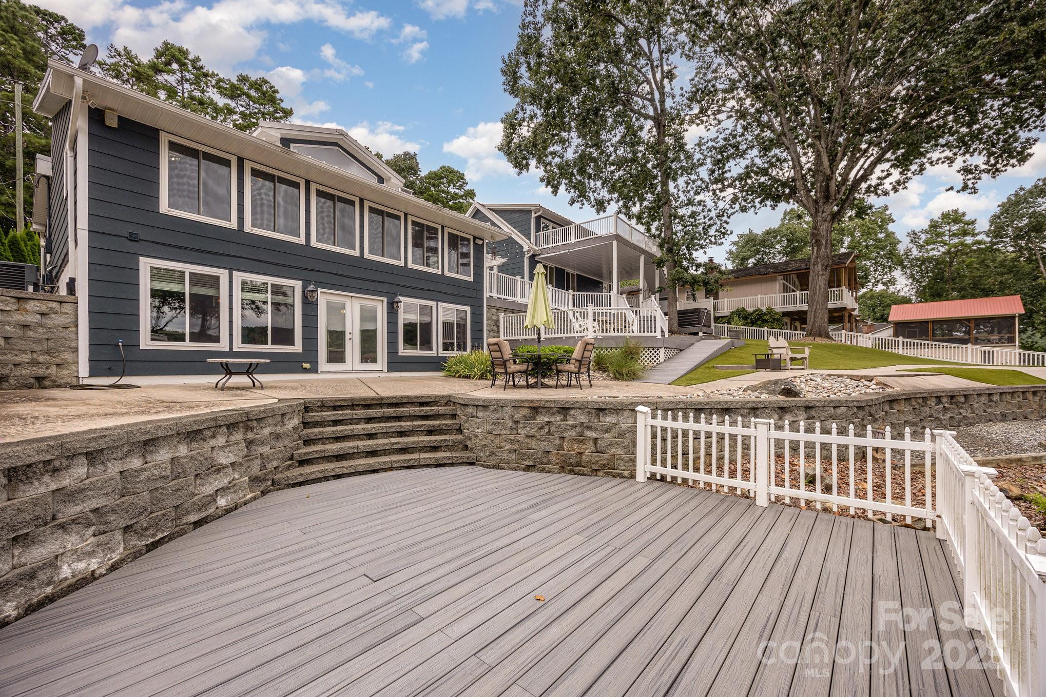 Amazing 100 ft of waterfront (.26 acre) with multi-level areas, plenty of space for entertaining. Fenced yard offers vinyl railings and trex decking on all levels including the boat dock.  Covered boat slip with cable lift (5500 lbs capacity) and 2 jetski floaters.  This FULLY FURNISHED home offers lots of natural light flowing through the wall of windows to enjoy the lake views from the open floor plan on the main level as well as the walkout basement. Home offers 4 bedrooms  (2 bedrooms in basement without windows). Both levels offer a full bath, basement laundry in utility room. Large family room with mini kitchen in walkout basement. Enjoy the wood burning fireplaces to warm on cool evenings or relax in the hot tub. Detached 2 car garage (built in 1980) and driveway offers ample parking. Garage has storage areas inside and out, half bath and additional bonus room living space above garage with large deck to enjoy views of the spacious patios and waterfront.  Sunrise mornings and mirrored sunset evenings await.