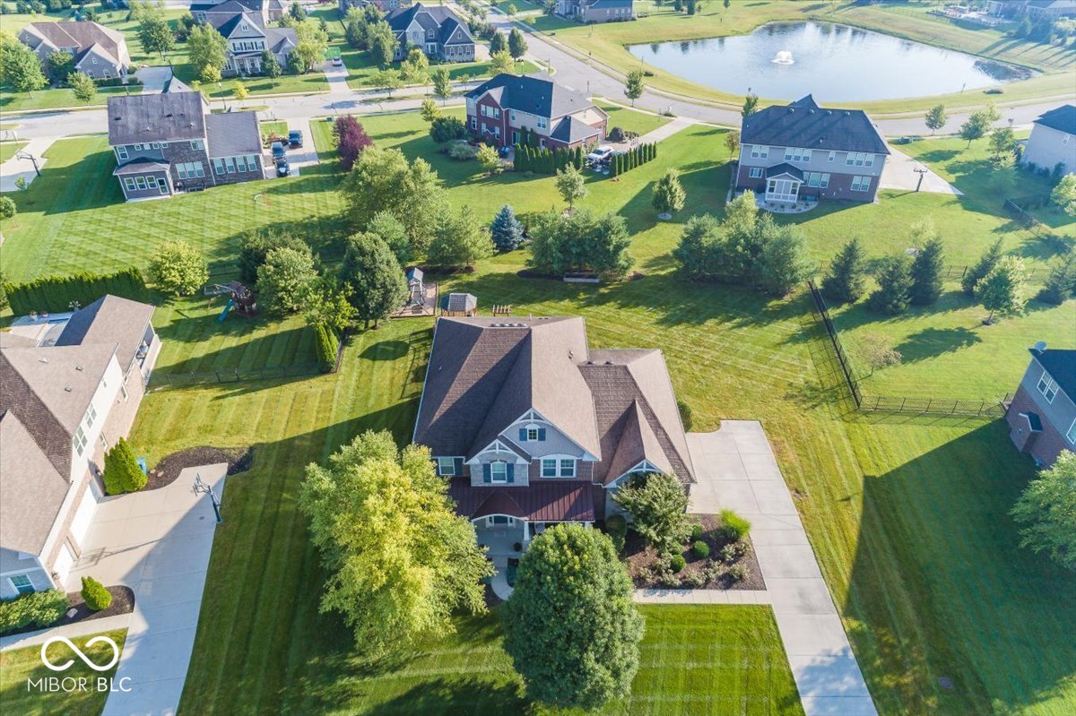 Desirable Location in Ravinia of Fishers. Great Curb Appeal with Inviting Front Porch. Enter onto Rich Hardwoods thru-out Main Level, Extensive Trim and Moldings, 10' Ceilings and Open Floor Plan. Great Room is open to Wonderful Kitchen with extensive Cabinets, Long Granite Counters and a Huge Island. Family Room has Plenty of oversize Windows. Private Den/Office features Glass doors. Upper Level has 4 Bedrooms, 3 Baths and Laundry Room. Primary Bedroom includes a large Sitting Area, Spacious Bath w Dual Vanities, Large Soaking Tub, Oversize Shower and Walk-In Closet. Bedrooms #2 and #3 have a Jack & Jill Bath #4 has Private Bath. Full Finished Basement has second Kitchen/Wet Bar with extra Cabinets and Granite, Media/Theater Room, 24x20 Play/Rec Room, 5th Bedroom and 4th Full Bath. Note, 3 Egress windows to allow extra light into these areas. Outdoors you can enjoy the Oversize Lot of .56 Acres, Mature Trees and Landscape, a Covered Patio w/Fireplace, Huge Deck w/Gazebo, Playground area w/Playset. Front of Homes overlooks the Large Neighborhood Pond with 2 Fountains. Community Swimming Pool and Rec Area are optional. Come and Enjoy!