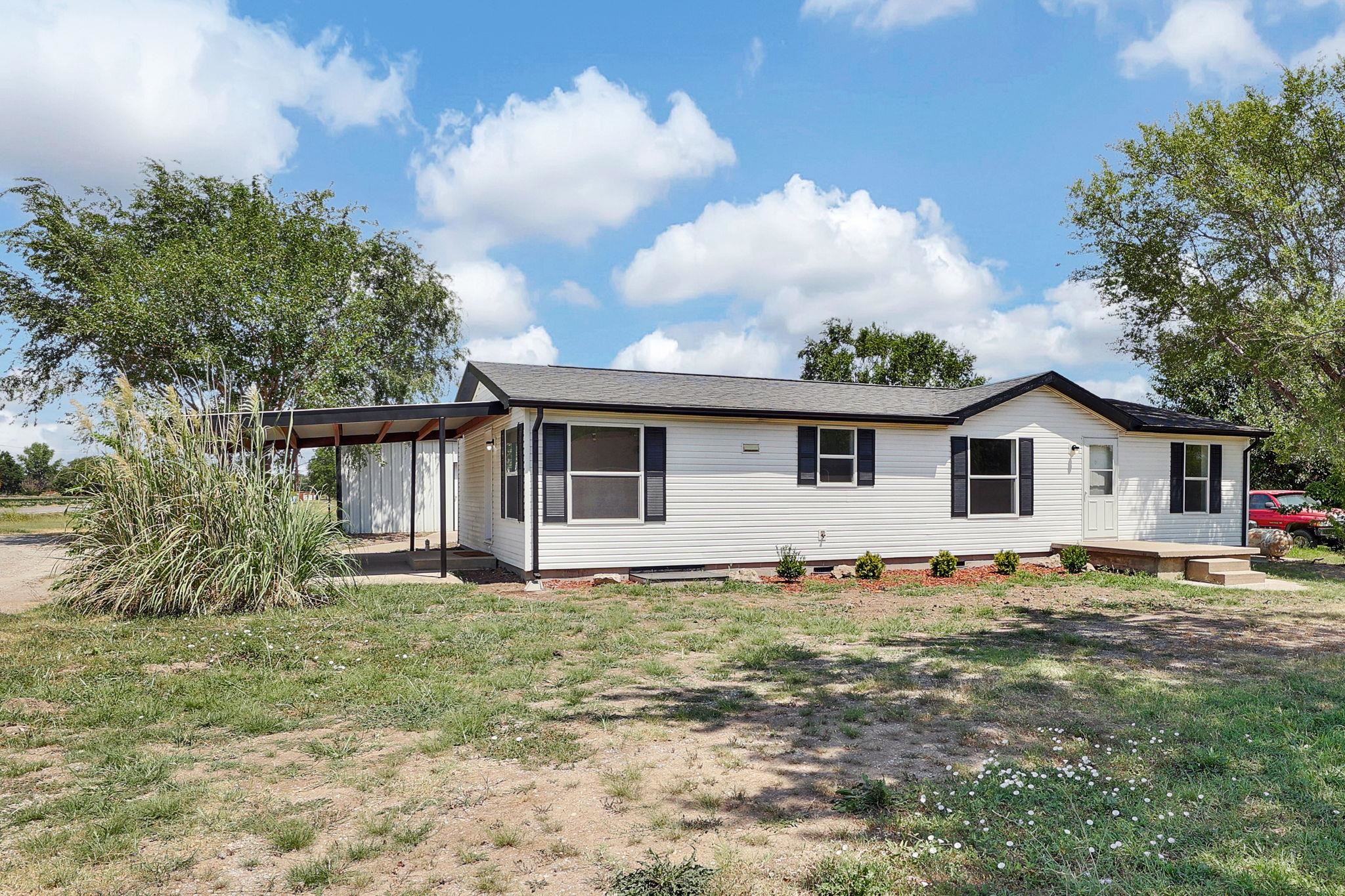 Who is looking for highly sought after shop space?  Check out this nicely updated manufactured home that sits on a permanent foundation with 3 bedrooms and 2 bathrooms.  This split bedroom floor plan has plenty of room to spread out.  The kitchen has ample counter space and cabinets along with new counter tops and back splash.  The seller has just freshly painted the home and all of the flooring is brand new.  The windows are also brand new.   There is a 30x30 metal building in the back yard that has a built-in storm shelter.  The home is connected to septic system and has just recently been connected to city water. The property sits on the corner and has drive way access from 2 sides.