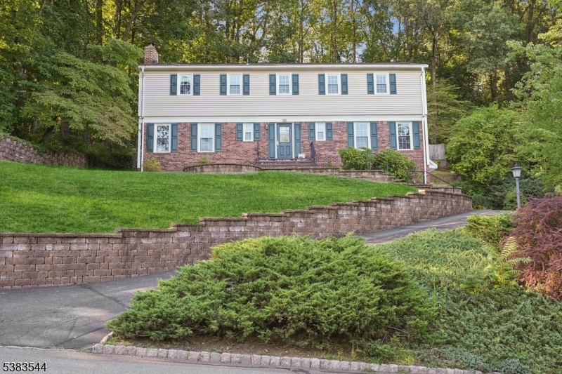 Situated in a desirable neighborhood, this home offers a versatile layout with tremendous potential for customization and updates. The first floor features a welcoming foyer, a spacious living room with a cozy fireplace that flows into a formal dining room, a bright den and a powder room. The eat-in kitchen with a peninsula and wood cabinets overlooks an expansive deck, ideal for entertaining or enjoying morning coffee, and a convenient first-floor laundry adds everyday ease. Upstairs, the primary suite boasts a large walk-in closet and also includes a private full bathroom with a newer stall shower, while three additional guest bedrooms feature plenty of closet space and share a full hallway bathroom. The lower level provides a spacious recreation room, a massive storage room, and a two-car garage. Outside, the home offers amazing views of the rolling hills in the distance while the tranquil backyard creates an inviting space for gatherings and al fresco dining. Additional highlights include furnace & central air (only 6 years old), Wolf composite deck, replacement windows (approx. 10 years old), hardwood floors under the carpeting, 200 AMP panel, attic storage, gas line to grill, and the large driveway offers plenty of off-street parking. With its well-thought-out floor plan and multiple living spaces, this home offers the perfect opportunity to create a home tailored to your lifestyle and design preferences. Convenient to top-rated schools, parks, shops & NYC train.