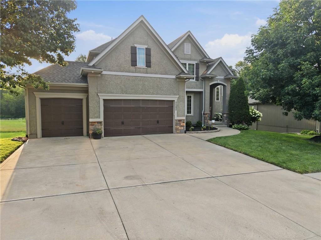 Welcome to 1502 Cross Creek Drive in the highly sought after Creekmoor subdivision of Raymore, Missouri. This stunning two-story home offers over 4300 sq. ft. of beautifully finished living space, five bedrooms and four and a half bathrooms.  From the moment you arrive, the stone and stucco elevation, manicured landscaping, and oversized three-car garage make a lasting first impression. Step inside to discover a grand staircase with ornate wrought iron balusters, rich hardwood floors, and a gorgeous great room complemented by a bold gas fireplace and large windows with beautiful views of the backyard!  The gourmet kitchen is a showstopper with granite countertops, custom cabinetry, new pendant lighting, an expansive island perfect for meal preparation and a huge walk-in pantry for ample storage.  A charming half bath with designer wallpaper is conveniently located just off the kitchen and adjacent to the well-appointed mudroom lending to the perfect drop zone as you walk in from the garage. New carpet on the main and second level accentuates this incredible home!  Four additional spacious bedrooms offer flexibility for family, guests or a home office.  The primary suite is a true private retreat, featuring dual vanities, a corner jetted tub, a walk-in shower, and a massive walk-in closet. The finished walkout basement takes this home to another level with a stylish wet bar, recreation room, full bath, and a fifth bedroom. Step outside to the freshly stained deck overlooking the treed backyard and the fourth hole of the golf course. Below, the flagstone patio with a firepit creates the perfect setting for evening gatherings. Situated in the amenity-rich Creekmoor community, this ERS-certified energy-efficient green home offers both luxury and sustainability. Don't miss this incredible home! Hurry!