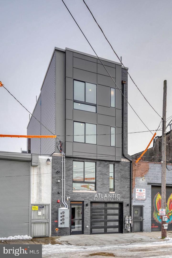 Run your business downstairs and let the tenants upstairs help pay for it. The ground floor at 1747 Tilghman is roughly 2,400 square feet across the first floor and a connected, finished basement — with its own kitchen, a full bath, a separate entrance off the street and a private garage at the rear. Built in 2019 by the contractor who owns it. The lease on that floor is reported to expire 10/31/2026 and convert to month-to-month, so an owner-occupant may be able to take the space in the near term, subject to the lease terms. Above it are two 2BR/2BA apartments, each with a private roof deck, in-unit laundry and central air, leased at $2,100 and $2,050 per month plus water. That income offsets much of the carrying cost while you use the floor below. Tax abatement in place. Tenants pay their own gas and electric. Zoned ICMX. Half a block to the Berks El; walk to Frankford Avenue and Front Street. 4,160 SF above grade. Potential uses are subject to zoning, licensing and buyer verification. Rent roll, leases and expenses available on request.