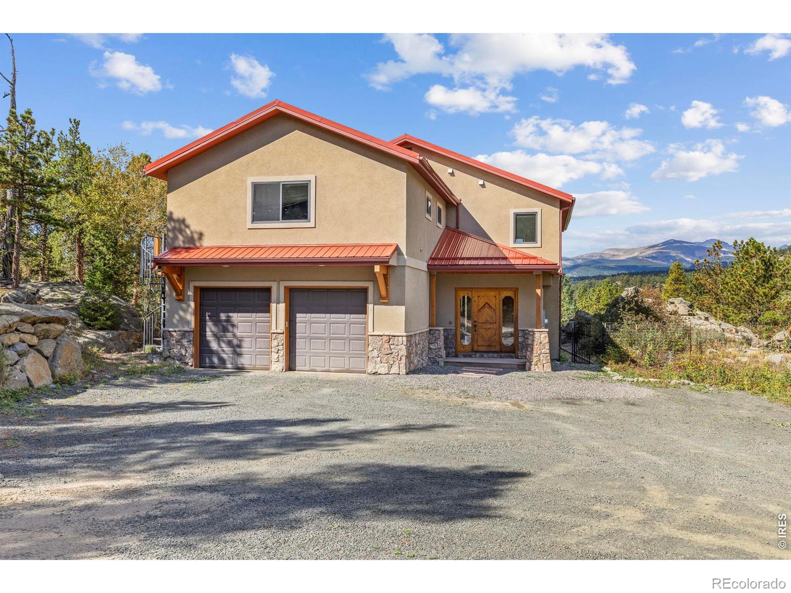 Located at the end of the road, this custom stucco home, built in 2007, occupies 7 private acres in a coveted neighborhood just minutes from Nederland, with 3 sides adjoining National Forest. Framed by dramatic rock outcroppings and sweeping snowcapped Indian Peaks views, this exceptional property offers refined craftsmanship, seclusion and direct access to nature. A private drive leads to a level parking area and oversized 2-car garage. Inside, the tiled foyer opens to an inviting open-concept main level designed for living and entertaining. The well-appointed kitchen features granite counters, a 4-person bar, stainless appliances and an oversized pantry, while the adjacent dining and living areas showcase newly refinished hickory floors, tall ceilings and a wall of windows capturing the mountain panorama. Step outside to a spacious composite deck and flagstone patio that leads to a hot tub nestled against tumbled boulders. A dedicated office with Murphy bed offers flexibility as a 4th bedroom, while a half bath completes the main level. Upstairs, 3 generous bedrooms accompany a massive rec room/flex space with balcony, views and a metal spiral staircase to the grounds. The primary suite is oriented toward the views and features an ensuite with soaking tub, separate shower and private balcony with spiral stairs to the deck. An owned solar system helps offset energy costs. A fenced yard provides space for pets or play, while rock outcroppings and a private trail system lead toward National Forest and miles of hiking from your doorstep. The basement offers potential for future finished space, with a finished laundry room already in place. A metal roof and new tankless water heater add to the home's enduring appeal. Just 10 minutes to Nederland and an easy, scenic commute to Boulder via the summer access road, this is a special mountain property with the quality, setting and timeless appeal to become a legacy home for generations.