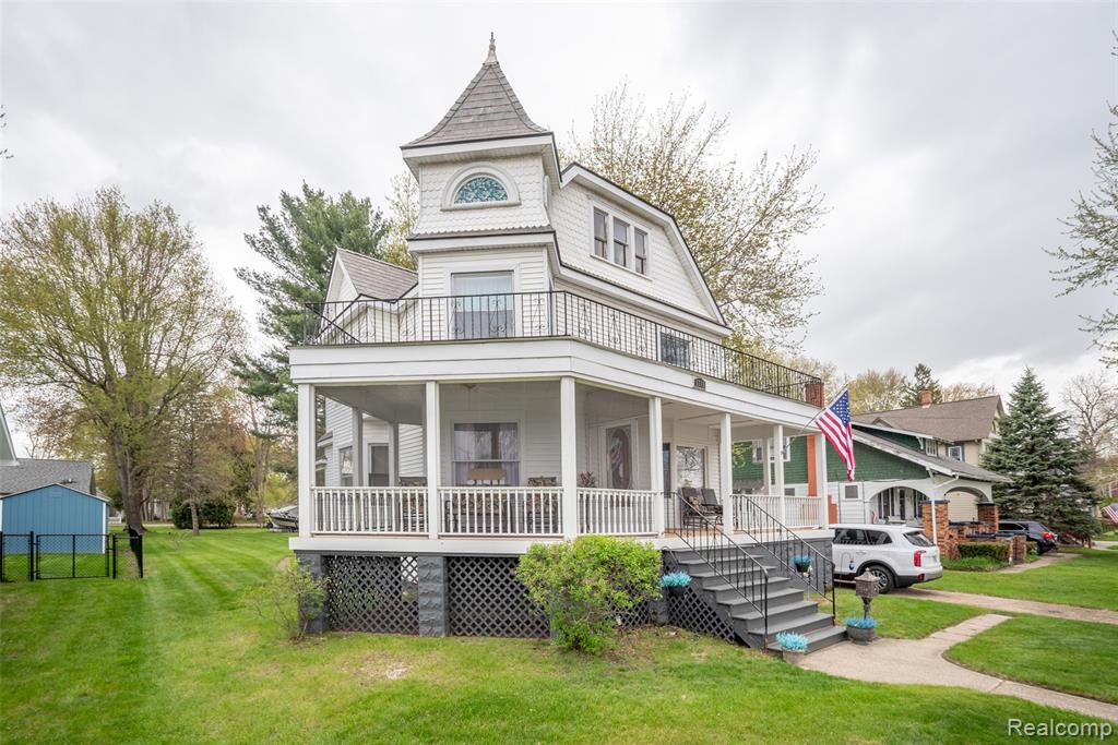 Algonac living is calling your name! Just a short walk to the St. Clair River, the city park, community pool, bike path, riverfront boardwalk, boat launches and marinas. This charming updated 1898 Victorian-style home is situated on a double lot and offers 4 bedrooms, 3 full bathrooms, and 2,013 SQFT of beautifully maintained living space. Full of character and timeless appeal, the home features refinished oak floors throughout, original period crown moldings, and many more classic architectural details. Enjoy relaxing on the wraparound porch with a screened-in section, ceiling fan, and a second-story balcony above. Inside, the spacious living room is filled with natural light and showcases views of the stunning staircase. The formal dining room features elegant ceiling trim, crystal chandelier, and a cozy natural fireplace with a carved wood mantle. The updated kitchen is complete with stainless steel appliances, a farmhouse sink, large floating island, crisp white LaFata cabinetry, quartz countertops, stylish backsplash, and a dedicated coffee bar area. A main-level sitting room with an adjacent full bathroom featuring a walk-in shower offers flexible use as a guest room, office, or additional living space. Upstairs, the primary suite includes a large ensuite bath and cozy sitting area. An additional bedroom, full bathroom with upgraded walk-in shower, convenient laundry closet, and a charming bedroom with beautiful wood accents and recessed lighting complete the upper level. The 3rd floor is unfinished and waiting for your personal touch to add additional square footage if needed. The basement is currently used as a workshop and houses a 2nd laundry area. Additional highlights include a slate roof (2016), an attached 1-car garage, shed, and a huge backyard with mature trees offering privacy and plenty of outdoor space. Schedule a showing today! BTVAI
