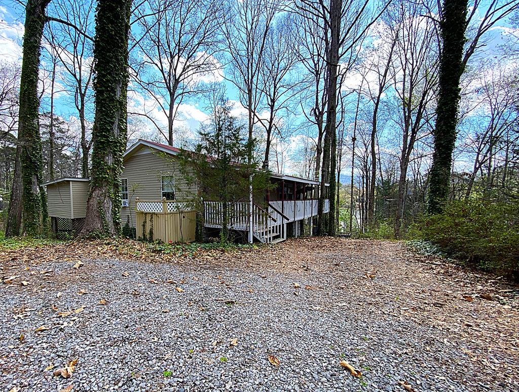 Have you ever wanted to live on a lake in North Carolina, but don't want to spend $1,000,000 to do it? Come tour this wonderful opportunity to own a large and versatile home in one of Hayesville, NC's picturesque lake front communities! This large and versatile home comes with a seasonal lake view and is within walking distance to its very own boat slip and boat! 3 bedrooms and 3 full baths make it plenty big enough to serve multiple purposes without feeling cramped and uncomfortable. Kitchen and living room are open to each other giving it an inclusive feeling for parties or a quite dinner at in. Primary suite with walkout access, guest room, guest bath, and laundry room are all on the main floor making day to day life in this house easy and convenient. Basement is roomy and includes a large open living area, 1 extra bedroom, full bathroom, and 2 other small hobby rooms or offices. Back deck is fully screened with a sunken hot tub deck and an open to the sky viewing platform. Pull in basement level garage is large enough to park a car AND have storage or workspace in the back. Enjoy all Hayesville lake life has to offer with this incredible opportunity in a serene lake front community just minutes from downtown Hayesville NC!