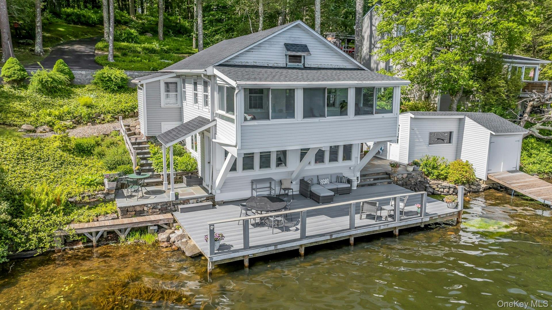 Welcome to your whimsical lakefront paradise on magnificent Lake Oscaleta! This charming, thoughtfully updated 1930s cottage offers a rare and magical opportunity to experience true waterfront living. Perfectly positioned right at the water’s edge, this two-bedroom, one and a half bath room retreat beautifully replicates the enchanting feeling of living on a houseboat, surrounded by panoramic nature and water views. Step inside to find a bright and cheery, modern kitchen equipped with new stainless steel appliances and an open dining area designed for seamless entertaining against a backdrop of spectacular lake vistas. The spacious living room serves as the heart of the home, featuring a cozy wood-burning fireplace that promises warm winter evenings. Transition easily into the adjacent enclosed sun porch, a serene space where you can savor morning coffee or unwind with sunset views over the tranquil waters. Outdoor living is unmatched here. Step out onto the large deck perched directly at the water’s edge, or enjoy the sweet, private patio located right off the kitchen—ideal for al fresco dining. A standout feature of this property is the separate, detached boathouse with a private dock. This unique structure offers endless future possibilities: perhaps an inspiring lakeside home office, a quiet artist's studio, or a spectacular recreation space. Lake Oscaleta is a pristine freshwater haven connected by direct water channels to both Lake Waccabuc and Lake Rippowam. Enjoy year-round recreation right from your backyard—swim, boat, kayak, fish, or ice skate. Whether you are seeking a full-time residence or a peaceful weekend escape from the city, this amazing home provides an unparalleled lifestyle. A very special and rarely available offering—you won’t want to miss this one!