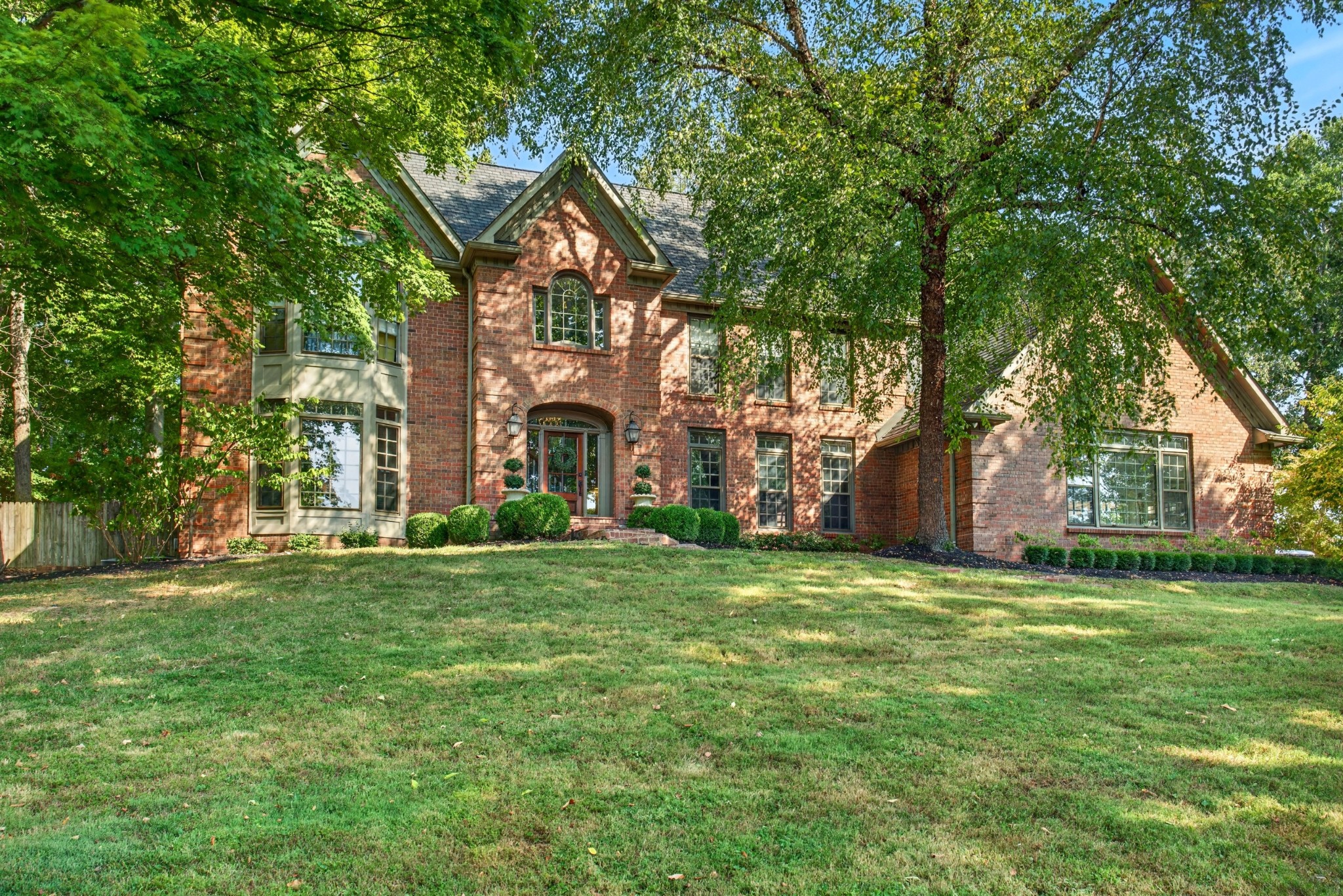 Some homes are beautiful, but some homes have a presence that simply cannot be recreated—and this is one of them. Set in one of Clarksville’s most coveted settings, this distinctive traditional home offers an extraordinary combination of character, craftsmanship, privacy, and views, overlooking the Red River, Clarksville Country Club and River Club golf courses.From the moment you arrive, the architecture sets the tone. The classic brick exterior, mature trees, beautifully established landscaping, arched entry, and timeless details create an immediate sense of warmth and permanence. This is a home that feels as though it belongs here—and has for generations. Inside, the character only continues. Rich hardwood floors, beautiful millwork, a striking traditional staircase, detailed trim, arched doorways, and thoughtfully selected wallpaper create rooms that feel collected rather than simply decorated. The home embraces traditional Southern style with an inviting, comfortable sensibility. Rich wood accents, a beautifully detailed coffered ceiling, classic fireplace, layered textiles, antique-inspired furnishings, and abundant natural light give the living spaces an unmistakable warmth.The floor plan is equally special, offering rooms with purpose and personality while maintaining an easy flow for everyday living and entertaining. Large windows throughout invite the surrounding landscape in, allowing the setting to become part of the home itself. This is more than a house—it is a home with a history, a personality, and a story still being written. A truly special Clarksville property for those who appreciate timeless architecture, beautiful surroundings, and a home that feels like it has always belonged.