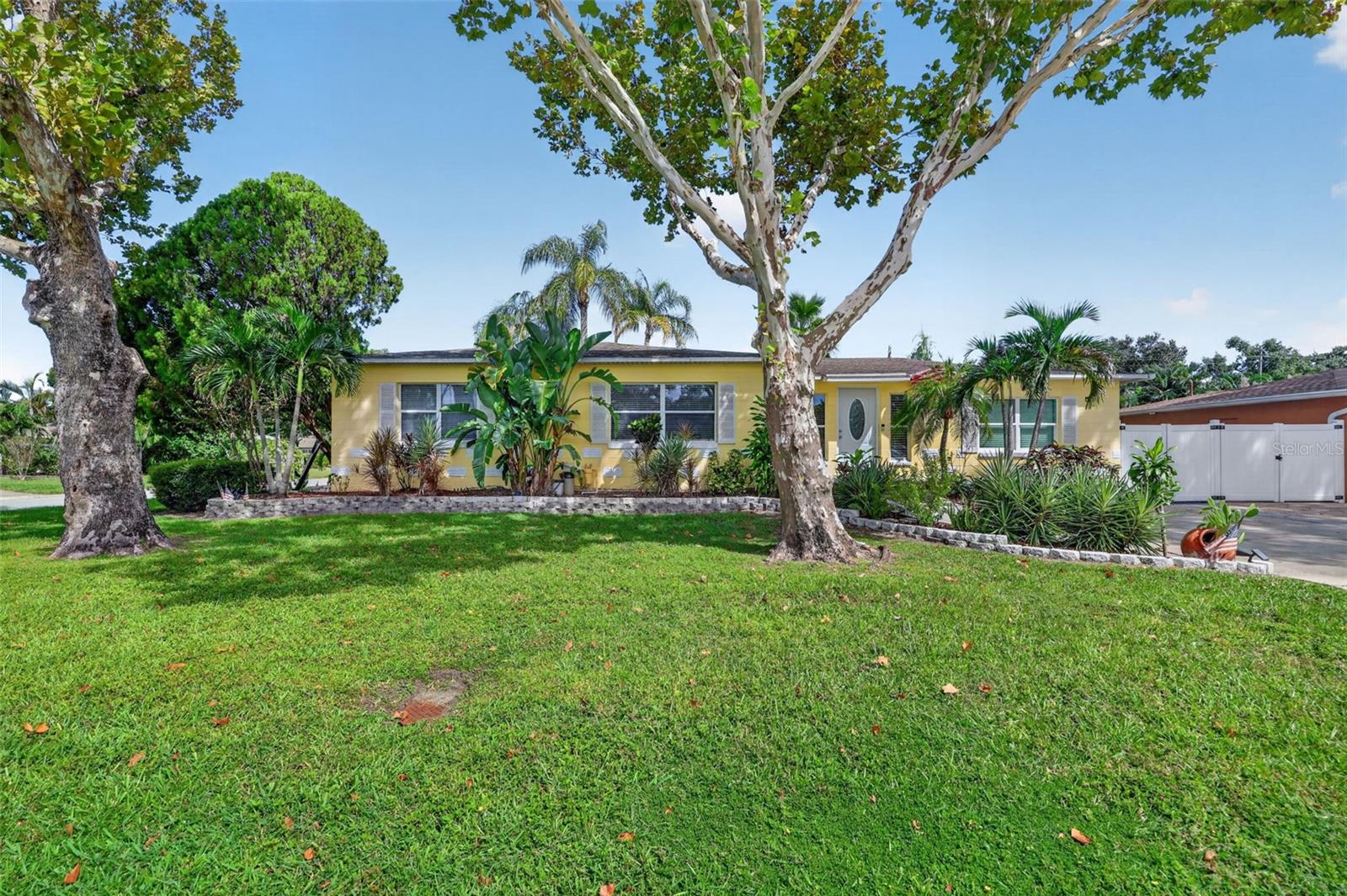 Located in the heart of St. Pete, this recently updated 3-bedroom, 2-bathroom home is filled with coastal cottage charm and modern elegance. Step into an open foyer with an abundance of natural light, vaulted tongue-and-groove ceilings, and beautiful exposed beams.The spacious kitchen features solid hickory cabinetry, recessed lighting, a classic copper-style backsplash, induction cooktop, sparkling granite countertops, newer appliances, and a huge bar perfect for entertaining. The home’s open floor plan creates a seamless flow from the kitchen into the bright living room, which showcases a decorative fireplace, 5” baseboards, chic cove-ceiling accents, and plenty of natural charm. The formal dining room includes boutique lighting, glass sliders, and a built-in dry bar or serving area. This split floor plan offers two generous bedrooms with deep closets and built-ins, along with a modern, beach-inspired hall bathroom featuring beautiful stained-glass accents that add color and character to the space. On the opposite side, the stunning primary suite features high ceilings, exposed beams, a solid alder wood door, access to the indoor laundry room, and a covered travertine lanai. The updated primary bathroom continues the coastal feel with a stylish sliding wood barn door.Outdoor living is just as impressive. A large, covered deck—accessible from the dining room and third bedroom—spans nearly 700 sq ft and offers bar tops, electricity, and hardwired lighting. Just outside the primary bedroom, you’ll find a relaxing hot tub, creating a private retreat.The expansive fenced backyard includes lush green space, tropical plants, a private putting green, and plenty of room to unwind. On the west side of the yard, two spacious storage sheds (8’x12’ and 10’x20’ with roller door) plus a remote-controlled double gate allow for RV or boat parking behind the fence.Updates include an efficient 4-zone mini-split A/C system, an updated 200-amp electrical panel, whole-house Rainsoft water softener system, newer windows and doors, a generator for added peace of mind, and wind-mitigation features including hurricane clips.Located in a peaceful, established neighborhood within walking distance of Leslee Lake Park, and offering quick access to Downtown St. Pete, top shopping, dining, entertainment, and award-winning Gulf beaches.