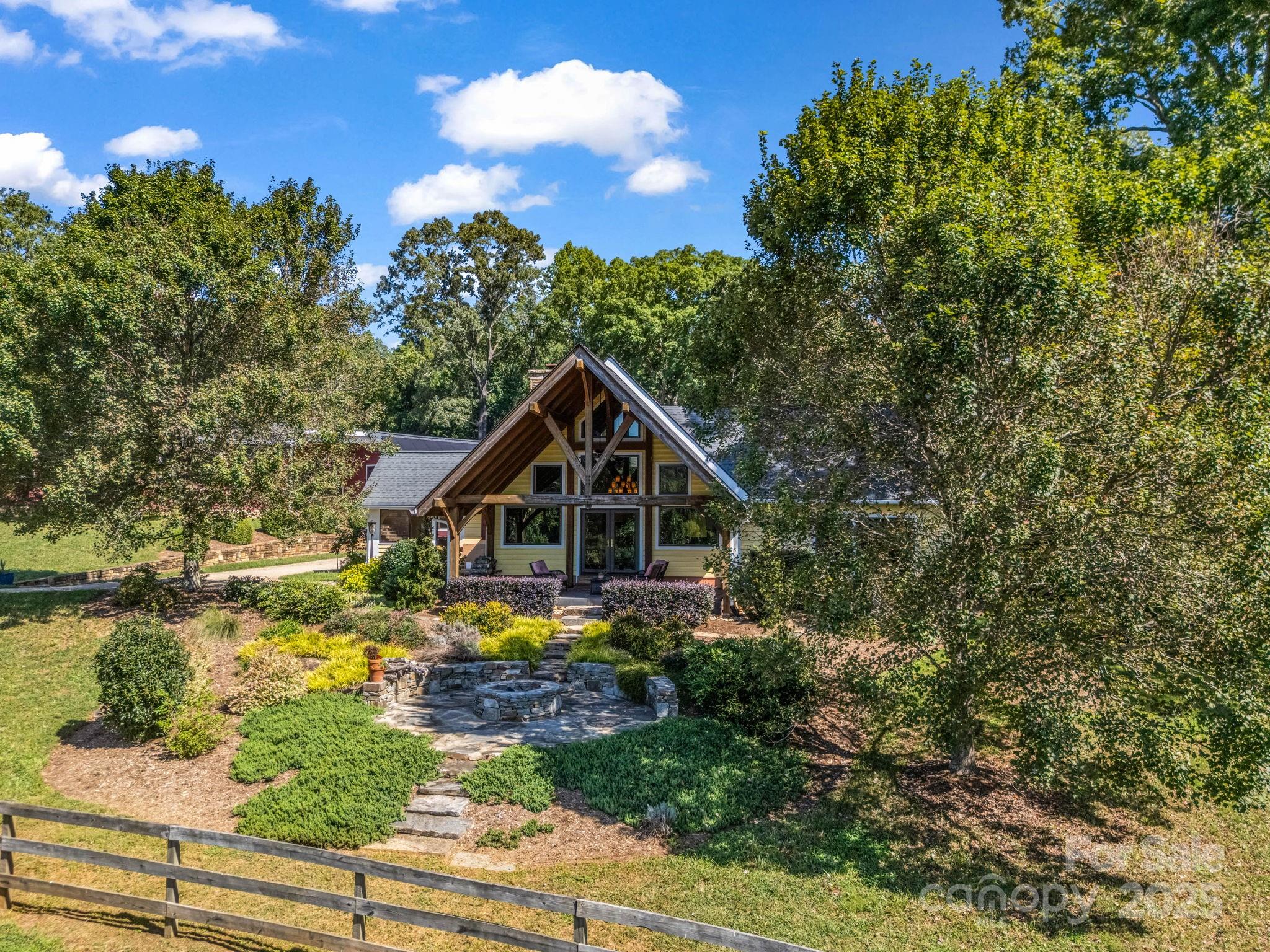 PRICE IMPROVEMENT!!  Welcome to Back Stretch Farm—where country charm blends seamlessly with practical equestrian living in scenic Tryon, NC. Nestled on 20 gently rolling acres with direct F.E.T.A. trail access, this property is a dream for horseback riding and outdoor adventures. Surrounded by conservation lands protected from future development, Back Stretch Farm offers unmatched privacy and lasting natural beauty.
The custom post-and-beam hybrid home features 3 inviting bedrooms, 3 full baths, and warm, sunlit gathering spaces designed for family and friends. A custom-designed barn includes 4 stalls, a center aisle, a workshop, and generous equipment and hay storage.  A conditioned tack room with full bath, laundry and living accommodations.  A second barn offers a run-in shelter that could easily be enclosed to create additional stalls.
Fenced and cross-fenced pastures include additional run-in shelters, ideal for horses and hobby animals. For competition riders, an all-weather footing  arena provides year-round training opportunities, while the wooded sections of the property promise peace, seclusion, and room to explore.
Located just minutes from the welcoming town of Tryon and the world-class Tryon International Equestrian Center, this rare offering combines the best of country living with proximity to top equestrian events. Back Stretch Farm is a unique horse-country haven—schedule your visit today and experience its charm for yourself.