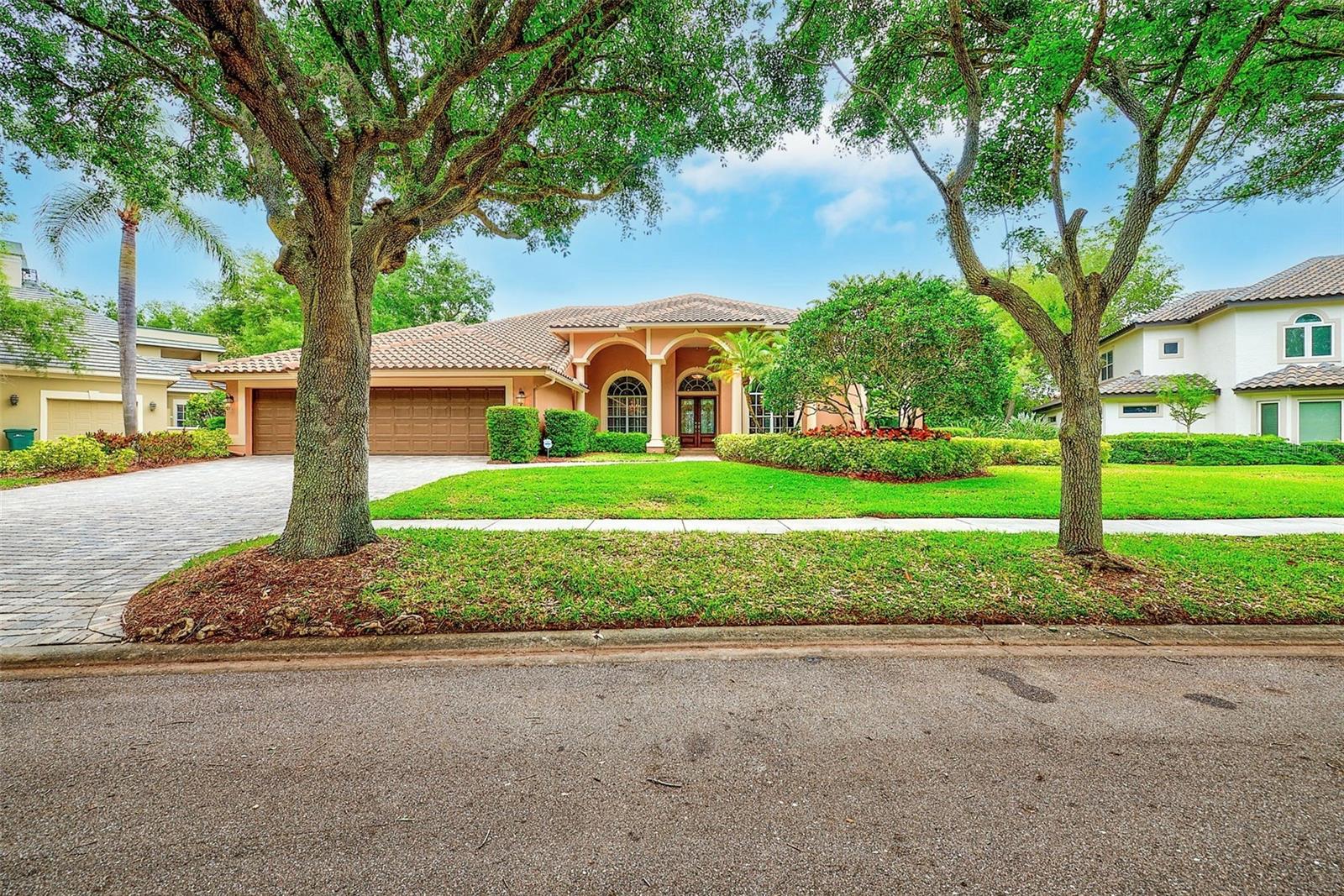 Welcome to 7640 Hunter Lane, located within the exclusive, guard-gated community of Bayou Club Estates. This meticulously maintained, one-owner residence offers 4 bedrooms, 4 full bathrooms, a private home office (or optional 5th bedroom), and a 3 car garage with professionally finished epoxy floors. From the moment you enter, soaring ceilings, abundant natural light, and elegant formal living and dining spaces set the tone for refined living. The thoughtfully designed split floor plan provides privacy and versatility, ideal for both everyday living and entertaining. At the heart of the home, the spacious kitchen features a large center island with cooktop, wall oven and microwave, custom cabinetry, granite countertops, and generous storage. It opens seamlessly to the family room, complete with custom built-ins and direct access to the outdoor living space. The expansive primary suite is a true retreat, offering private access to the pool, along with a spa-inspired bath featuring gorgeous marble floors, dual vanities, a walk-in shower, jetted tub, and two walk-in closets. On the opposite side of the home, three additional bedrooms and two full baths provide comfortable accommodations for family or guests, while a dedicated office on the primary wing offers flexibility for remote work or additional living space. Step outside to your own private oasis—an impressive screened lanai with a heated, resort-style pool and stunning waterfall feature, perfect for year-round Florida living and entertaining. Additional highlights include a large indoor laundry/mud room with plenty of storage, custom sound system, outdoor shower, newer roof (2021), newer HVAC systems (2019), water softener (2021), and exterior paint (2021). Bayou Club Estates offers 24-hour guard-gated security and an exceptional lifestyle. Residents have the option to join the Bayou Golf & Country Club, one of Tampa Bay’s premier private clubs, featuring championship golf, tennis, pickleball, fitness center, pool, and private clubhouse. Ideally located just minutes from award-winning Gulf beaches, fine dining, airports, and top amenities, this home presents a rare opportunity to enjoy luxury living in one of the area’s most sought-after communities.