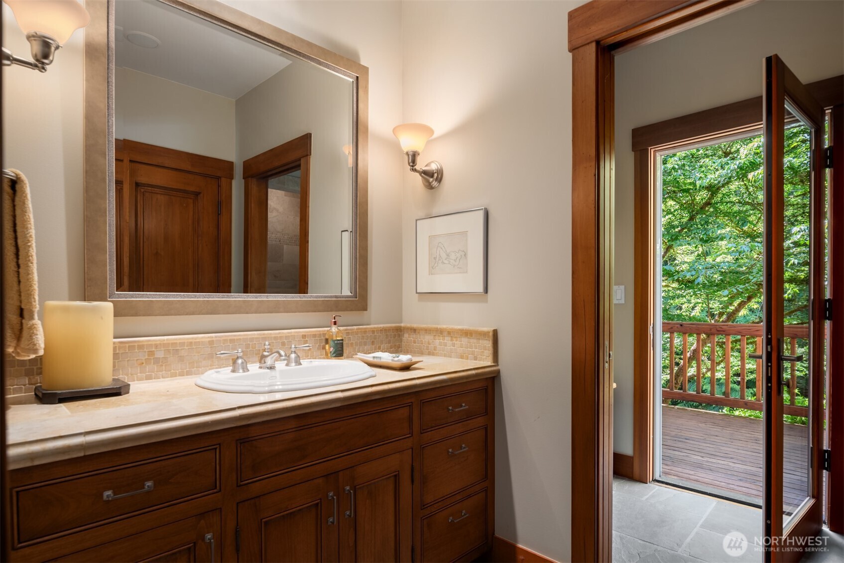 Bathroom with wood vanity, tile backsplash, and door to deck