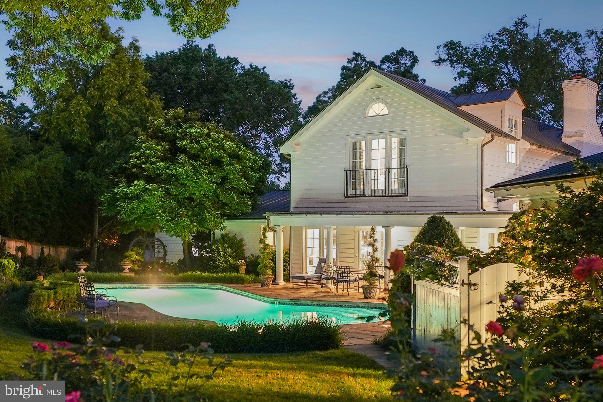 NEW PRICE! Nestled on the highest point of exclusive Mansion Drive—an intimate enclave of just 31 homes—this secluded and private 1.37-acre estate offers a once-in-a-generation opportunity to own one of Alexandria’s most celebrated private gardens. Forty years in the making, the grounds are a breathtaking tapestry of color, texture, and design, with rose gardens, oversized sculpted boxwoods, raised vegetable beds, mature and rare specimen trees, native plants and a sweeping open lawn ideal for grand events. Multiple national and state garden tours have featured this remarkable landscape, including many arranged by the Head Gardener at Mount Vernon Estate.  Meticulously maintained, multi-zoned irrigation system ensures its vibrancy year-round.The garden seamlessly incorporates a serene pool into its landscape, while a fully fenced backyard enhances privacy and security. Within the garden stands a classic Alitex glass conservatory imported from England and wired with electricity—perfect for seed propagation, potting and more.The main residence is a beautifully crafted 5,119 sq ft home, blending timeless design with modern comfort. A rare main-level primary suite anchors its own private wing and includes dual full bathrooms and dual walk-in closets. Soaring ceilings—up to 12 feet—crown gracious living and entertaining spaces. Covered terraces at both the front and rear of the home invite relaxed outdoor living throughout the seasons.A charming guest house offers complete privacy for visitors or multi-generational living, featuring a full kitchen, living room, dining area, and bedroom with ensuite bath. Vaulted pine ceilings and a brick fireplace lend a warm, rustic elegance.A long private drive leads past the main residence to an oversized detached two-car garage. This iconic estate is also just minutes from St. Stephen's and St. Agnes Lower School and Alexandria Country Day School.This is more than a home—it's a legacy property for the most discerning buyer.