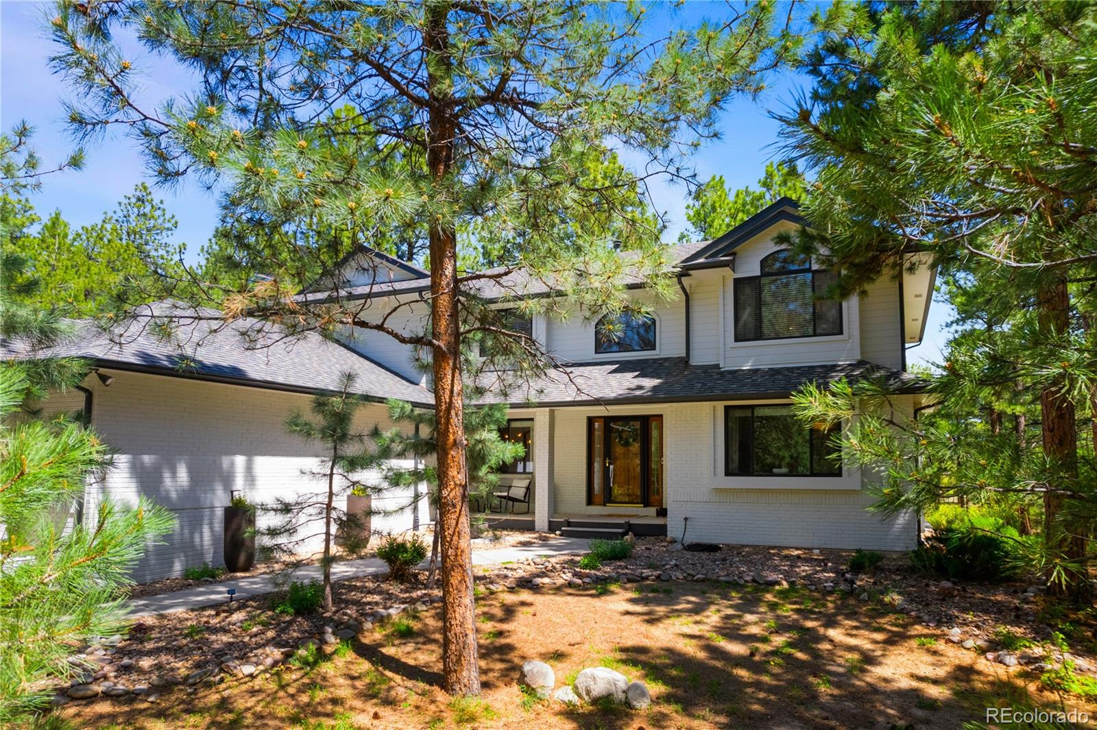 Sterling Pointe offers quintessential Colorado living, creating a daily retreat that feels like a vacation yet remains beautifully practical for everyday life. Tucked at the end of a quiet cul-de-sac in this tranquil Larkspur neighborhood, this home sits on two acres of privacy surrounded by mature pines, natural quiet, and a sense of calm that defines daily life. Minutes from Bear Dance Golf Club, consistently ranked among Colorado’s top places to play, the location blends forested seclusion with exceptional access. 

Inside, the architecture focuses on light and openness. Vaulted ceilings and walls of windows pull the outdoors in, filling the great room and kitchen with a natural glow. The main level includes a welcoming guest suite with deck access and a walk-in closet. Upstairs, the primary retreat offers elevated views and a quiet sense of removal that feels instantly restorative. 

When it is time to relax, the finished lower level provides generous space with a wet bar, recreation room, and a hidden gun room for secure storage. The oversized three-car garage features high ceilings and built-in storage to support projects, gear, and everything needed for adventurous living. 

Wildlife are regular visitors here. Deer linger by the front porch, wild turkeys cross the drive, and the occasional bear reminds you that this is true Colorado living. The outdoor spaces reflect that connection with a full-length deck and covered front porch. 

Although the setting feels peaceful and removed, access to Denver Metro, Castle Rock, and Colorado Springs remains simple and convenient. This is Sterling Pointe at its best: wooded acreage, privacy, and a home designed to live comfortably in its surroundings.