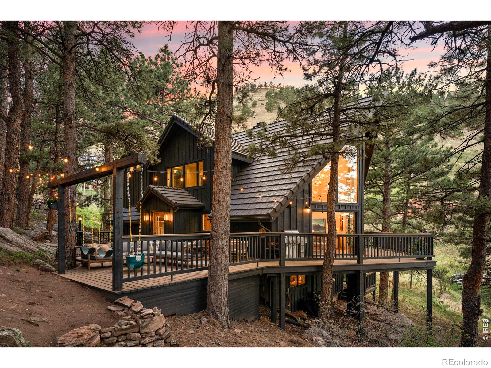 OPEN HOUSE SUNDAY 5/17, 10AM-2PM! Set on a rare and exceptionally usable 1.2 acres in Pine Brook Hills, this extensively reimagined mountain residence blends refined living with an unmatched connection to the natural beauty surrounding Boulder. Framed by a wide green meadow filled with deer, songbirds, mature pines & dramatic rock outcroppings, the setting feels private & serene while remaining just minutes from downtown. Thoughtfully transformed with a cohesive vision, the bright & airy interiors are grounded by white oak flooring & architectural details, curated lighting & carefully selected finishes that create warmth and continuity across the home. The vaulted main living area is crafted for both elevated entertaining and comfortable daily living with expansive windows & dual sliding glass doors opening naturally onto the wraparound deck. The kitchen balances beauty & functionality with custom cabinetry, soapstone countertops, integrated appliances, abundant storage & dedicated coffee station. A natural gas fireplace anchors the living space with warmth & ambiance. Beautifully refreshed guest spaces complete the main level while the lower level offers a private retreat ideal for multigenerational living or extended stays. Above, the primary suite provides a grand & peaceful escape with skylights, dual vanity ensuite bath with soaking tub, spacious walk-in closet with custom organization systems, private balcony, dedicated office space & loft overlooking the living area. The expansive deck is designed for memorable gatherings with a hot tub and outdoor movie screen surrounded by the quiet beauty of the foothills. Additional highlights include a detached two car garage with lower level workshop space, whole home generator, durable cement tile roof, highly regarded community water system & nearby fire protection services. A rare opportunity to own a thoughtfully transformed mountain property combining timeless style, usable land & close proximity to Boulder.