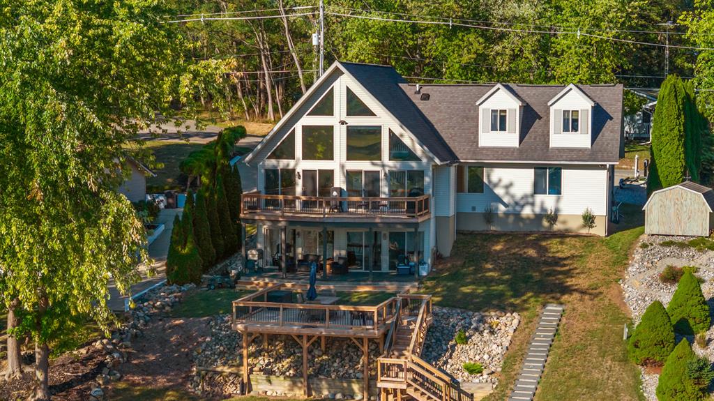 Welcome to your Private Lake Leann Masterpiece! This fully renovated, expansive waterfront retreat offers the perfect blend of modern luxury and all-sports lake enjoyment, situated on the desirable North Lake Leann. Experience breathtaking views from the moment you step inside. The main level boasts vaulted ceilings and a magnificent wall of floor-to-ceiling windows that frame the panoramic beauty of Waldron Bay. An open-concept floor plan connects the main living areas, making it ideal for large gatherings and entertaining. Recently completed, a stunning multiple-tiered deck system cascades down the hillside, creating the ultimate lakeside setup. You can enjoy the incredible higher elevation lake views while having functional, usable terraced space for relaxation and dining.This home is designed to comfortably host multiple families, featuring five total bedrooms including two separate private suites upstairs that offer retreats for primary residents or VIP guests, all supported bythree full bathrooms. The newly finished basement provides a second full living space perfect for game nights, a separate media room, or guest quarters, and features a lakeside wall full of windows, ensuring the stunning water views continue on the lower level.The sale uniquely includes a secondary lot across the street that has been professionally cleared, offering crucial, convenient storage for trailers, boats, and extra guest parking. North Lake Leann is renowned as an all-sports lake, offering something for everyone: no-wake bays are perfect for peaceful kayaking, canoeing, and paddleboarding, while the main lake is ideal for high-speed fun, including skiing and surfing. With multiple pull-up parks along the shore and a masterclass stocked fishery, you have a year-round opportunity to reel in that Master Angler-qualifying catch. This is more than a home it's a year-round lifestyle opportunity! Schedule your private showing today and step into your new luxury lakefront reality.