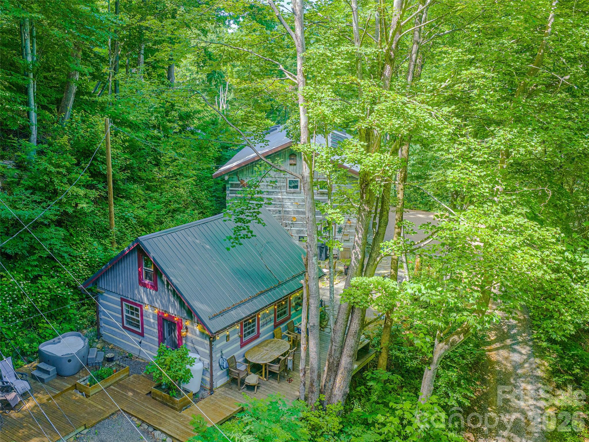Unique Artist Estate in the Cattail Creek Community! Private & remote location at 4,049’ Elevation with over 600’ of property boundaries shared with 2,000 acres of Mt. Mitchell State Park! Three unique buildings create the perfect live and work studio space. 600 amps of power on the property. Beautiful 20x20 hewn log small cabin has an open kitchen, living room, full bath + sleeping loft. Large 2 story hewn log structure is currently a glass studio, has a completely open floor plan with a fantastic loft & one half bath. Aprox. 3,000 sqft, 8 skylights & 19 Anderson windows, 2 car enclosed garage. Heated with wood pellet stove, could be finished out to be a home. Extra large metal building shop with 4 bay roll up doors. 6”-8” Concrete slab with Radiant floor heating keeps the workshop studio warm in the winter. Aprox. 2,100 sqft on the main level + 1,200 sqft of additional 2nd story storage.  Fantastic wrap around driveway allows for easy access to shop building. Small green house and flower beds. Call to schedule your private tour of this incredible property!