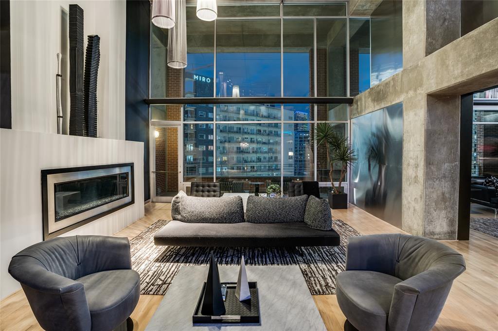 This Uptown contemporary loft condominium delivers-confident, elevated, and unapologetically stylish. With sweeping views of Downtown and Uptown, this two-bedroom, two-and-a-half-bath residence offers architectural edge paired with everyday livability. A rare four dedicated parking spaces further distinguishes the home in one of Dallas’ most walkable and connected neighborhoods.The open-concept living and dining areas are ideal for entertaining, filled with natural light and framed by skyline views that shift beautifully from day to night. A sleek dry bar anchors the space. Just beyond, the private terrace serves as a true extension of the home, offering rare outdoor living with panoramic city views.The kitchen, open to the main living space, continues the home’s clean, modern design with durable finishes. Both bedrooms offer a calm retreat featuring high ceilings, expansive windows, and a well-appointed ensuite bath. A dedicated home fitness area completes the residence. Enjoy walkable access to the American Airlines Center, Klyde Warren Park, the Katy Trail, luxury shopping, dining, and the Dallas Arts District—delivering true lock-and-leave living without compromise.