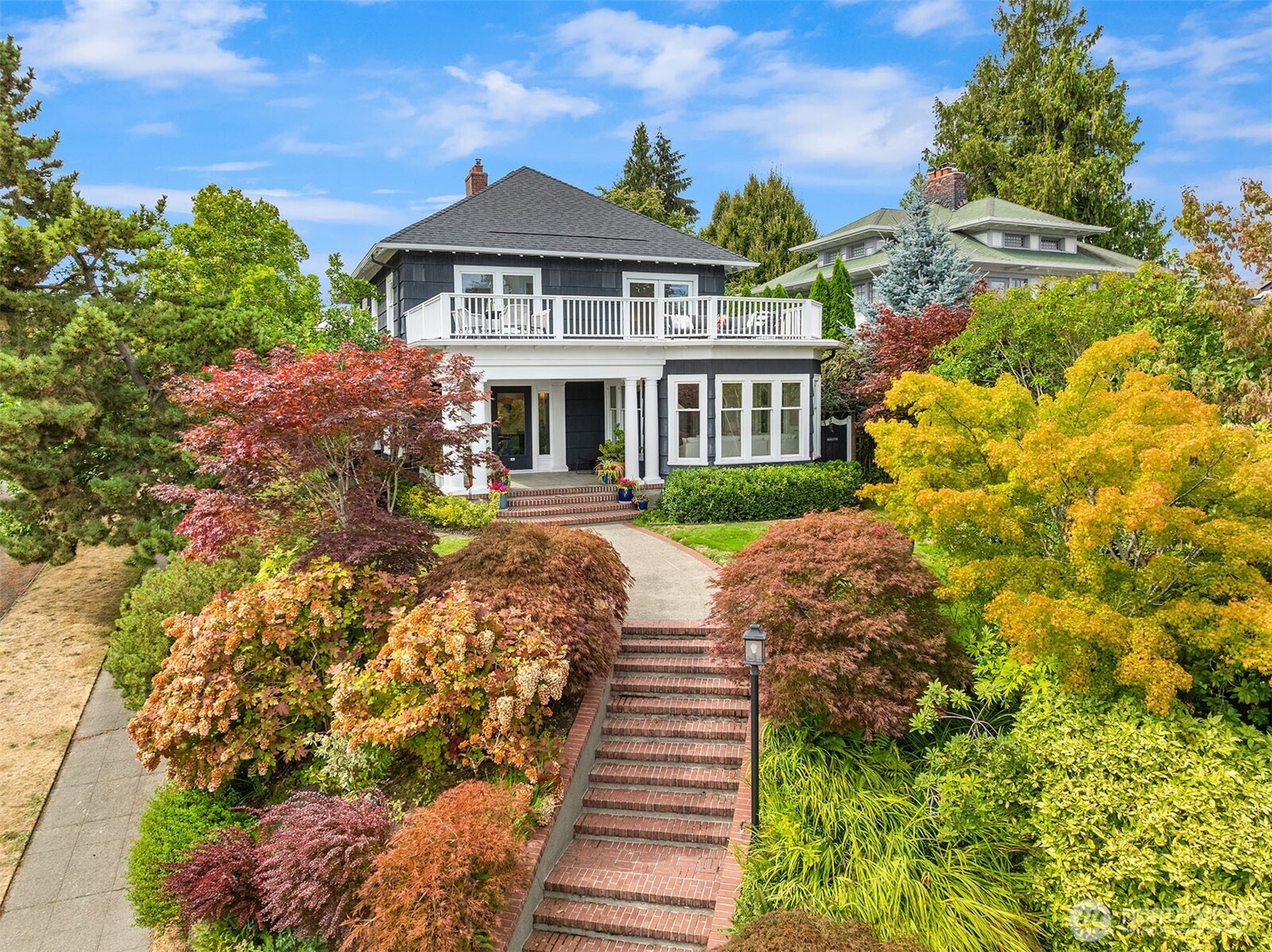 Stylish Colonial Revival with timeless appeal, thoughtfully updated while preserving its original architectural details. Perched up high on a southeast corner lot, this light-filled home offers multiple southern exposures and opportunities to enjoy the surrounding gardens, including a private deck off the kitchen designed for alfresco dining. Guests arrive in a grand foyer which opens to an elegant formal living room, a gracious dining room, and a connecting sunroom. The kitchen features a Lacanche range and charming breakfast nook. Upstairs, the primary suite captures unobstructed, sweeping views of Lake Washington from Mt. Rainier to Mt. Baker, including the Bellevue skyline. It features a spacious spa-like bath, deep soaking tub, large walk-in closet and an expansive balcony. Two additional upstairs bedrooms share a bath. A lower-level media room and laundry adds flexible living space. Attached two-car garage with alley access. Steps from Mioposto, Mount Baker Park, Lake Washington, tennis and pickleball courts and the Olmsted-designed lakefront paths, with downtown Seattle just minutes away.