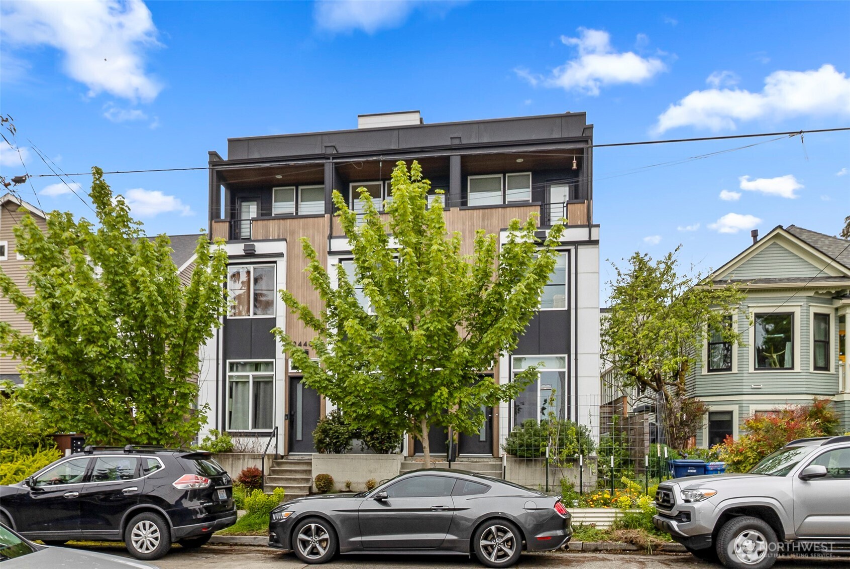 Beautiful modern 3-bed, 2 bath townhome (rowhouse) in the heart of Ballard — walk to everything. Situated on a quiet cul-de-sac,yet steps from the Ballard Community Center and playground, this home features hardwood floors throughout, sleek contemporary finishes, and abundant natural light. The open-concept living room flows into a designer kitchen with quartz counters and GE Profile stainless appliances, including a gas range—perfect for entertaining. The primary suite offers a private bath and ample closet space; two additional bedrooms provide flexible living arrangements. Comfort and efficiency are ensured by in-floor radiant heat served by a Rinnai tankless system, plus an LG ductless mini-split for targeted cooling and supplemental heating. Enjoy a private balcony, rooftop deck, low-maintenance landscaping, and one off-street parking space in a car-park courtyard. No HOA. Ideal for buyers seeking modern style, durable hardwood flooring, and year-round comfort.